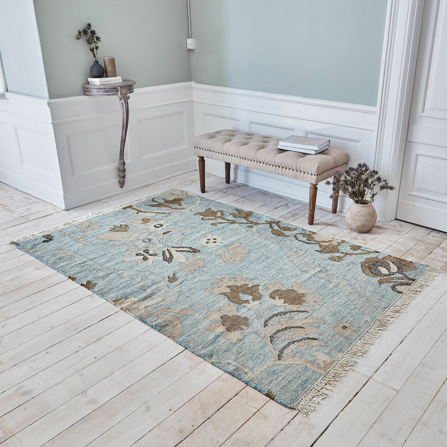 Tappeto Nére Tappeto con motivo floreale blu e beige su pavimento in legno chiaro in ambiente elegante