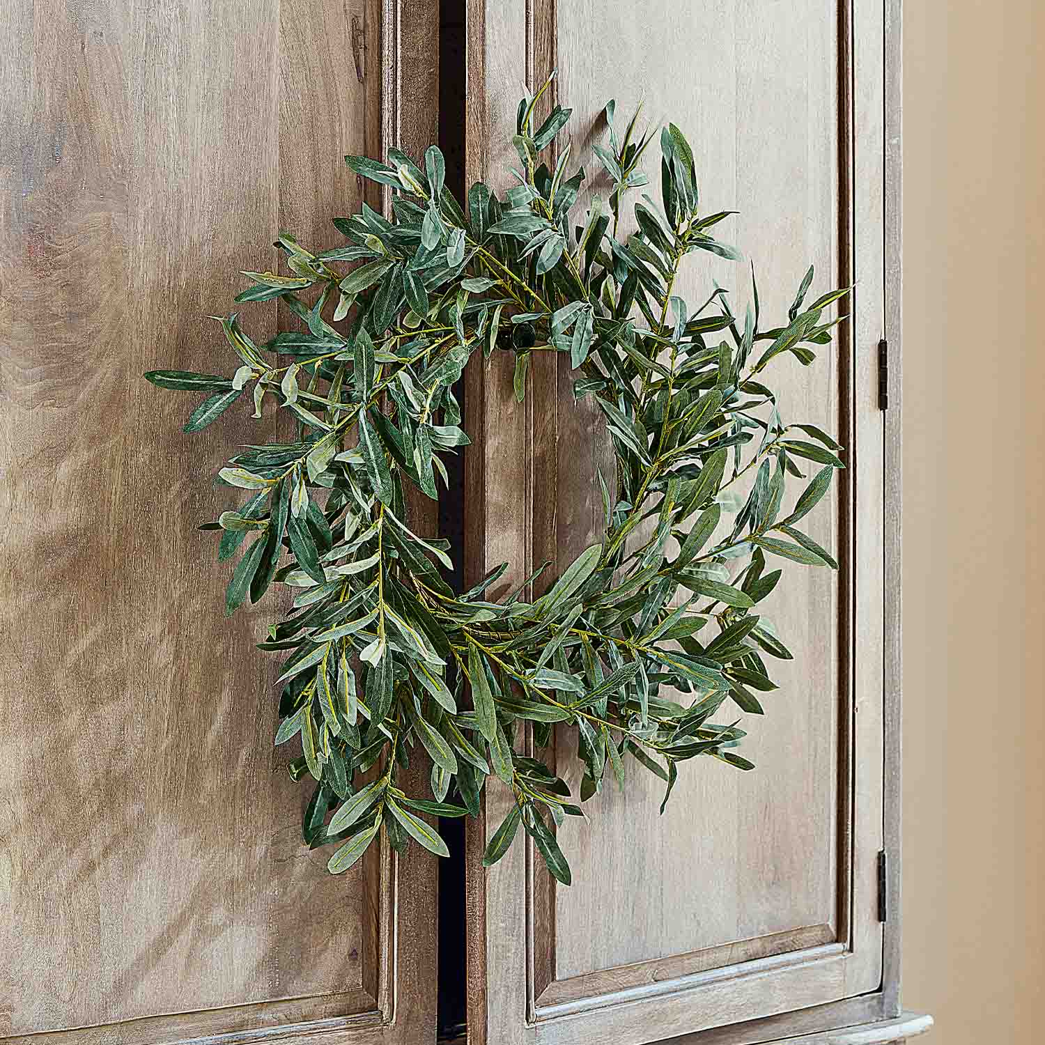Corona decorativa di foglie verdi appesa a porta in legno, decorazione naturale per interni