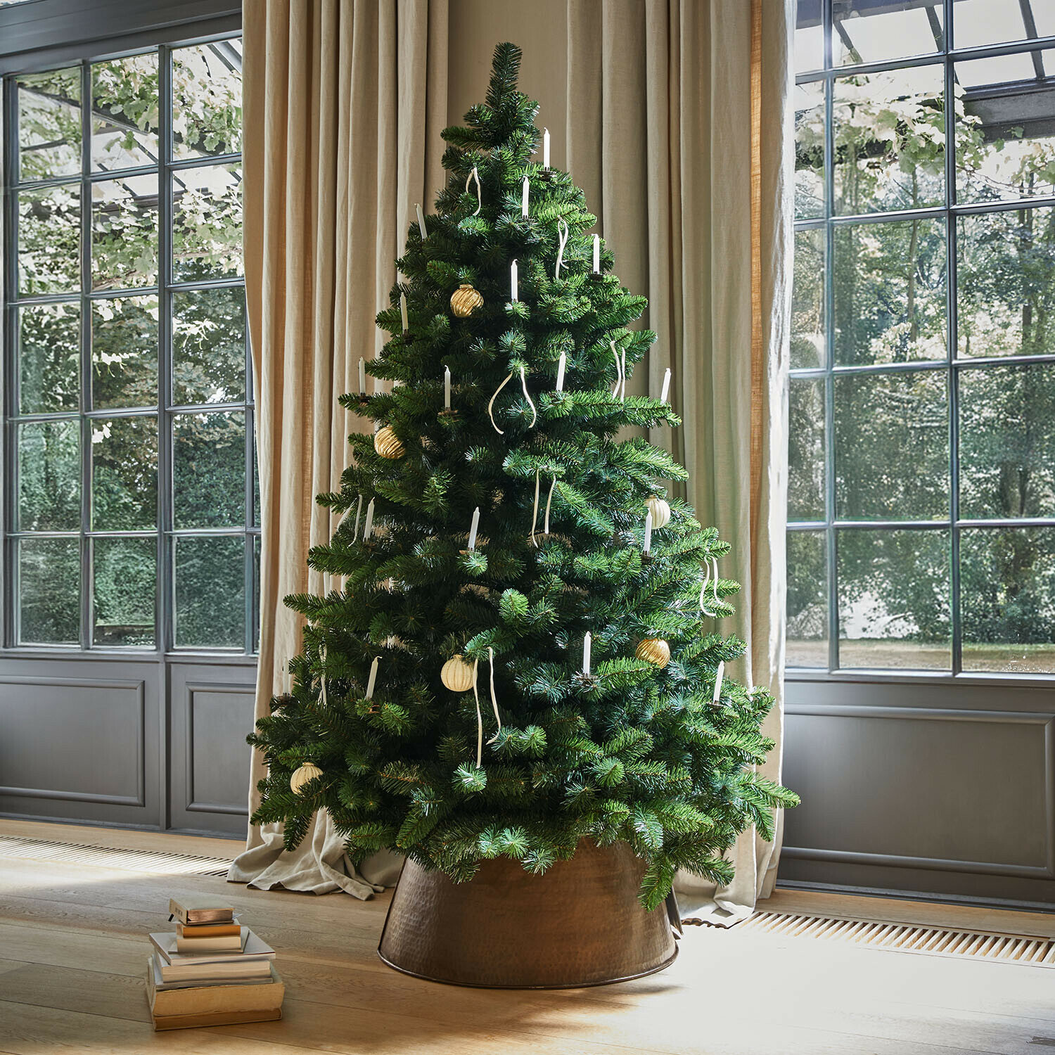 Albero di Natale Bryndis Albero di Natale artificiale verde con candele bianche in vaso di rame vicino a finestra con tende beige