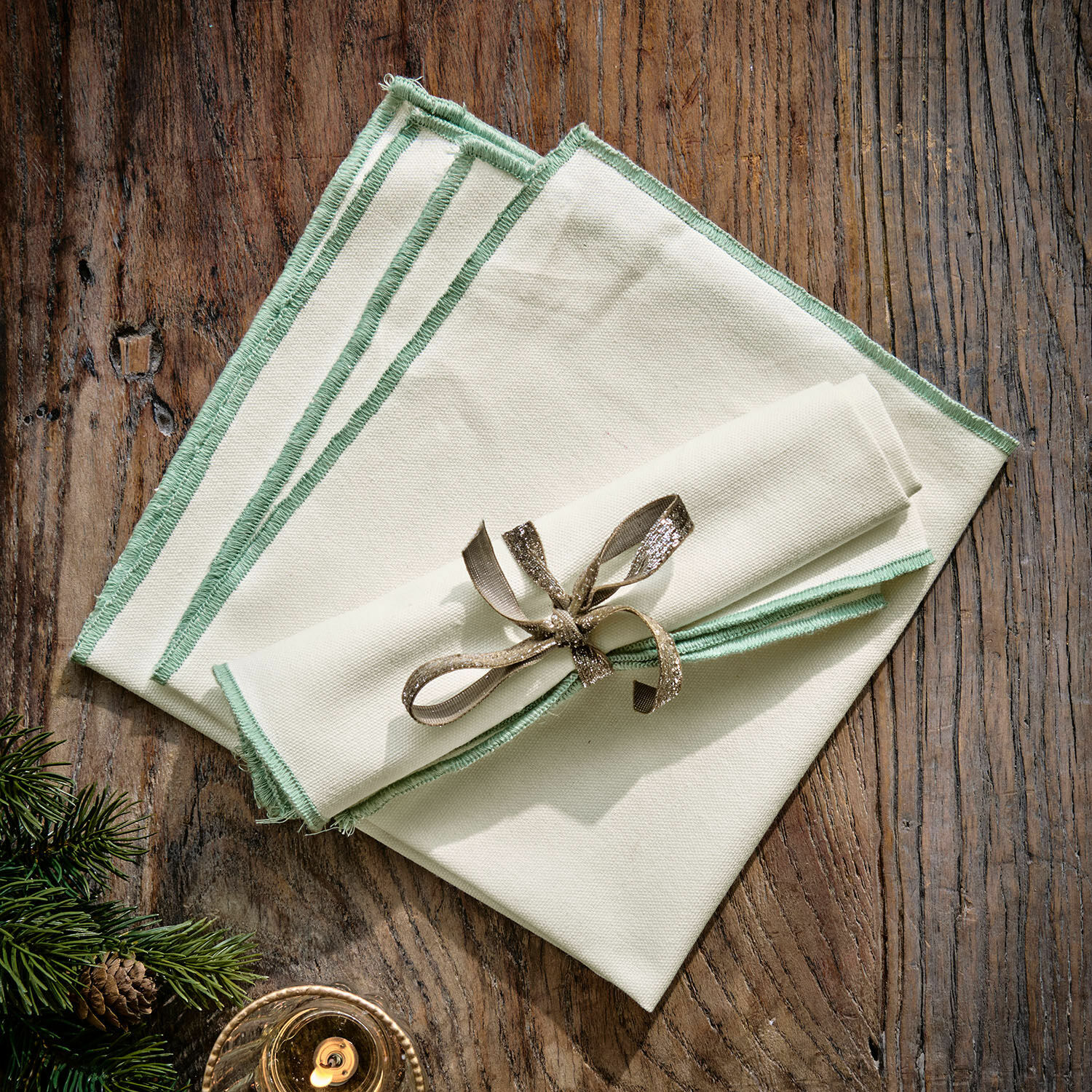 Coppia di tovaglioli Tarivelle Set di tovaglioli in lino crema con bordo verde su tavolo in legno, decorazione natalizia