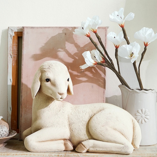 Figura decorativa di agnello chiaro accanto a vaso con fiori bianchi, ornamento per interni