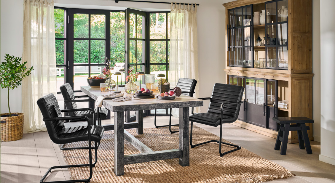 Sala da pranzo con sedie in pelle nera e tavolo in legno su tappeto naturale, stile moderno