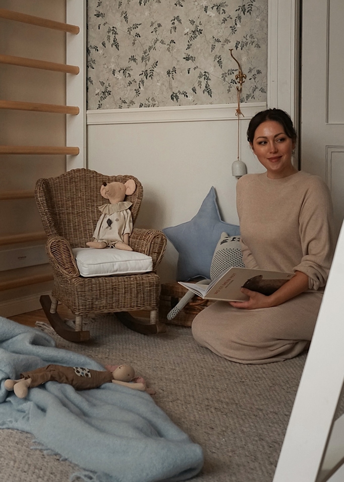 Angolo bambini accogliente con poltrona a dondolo in vimini e peluche su tappeto beige