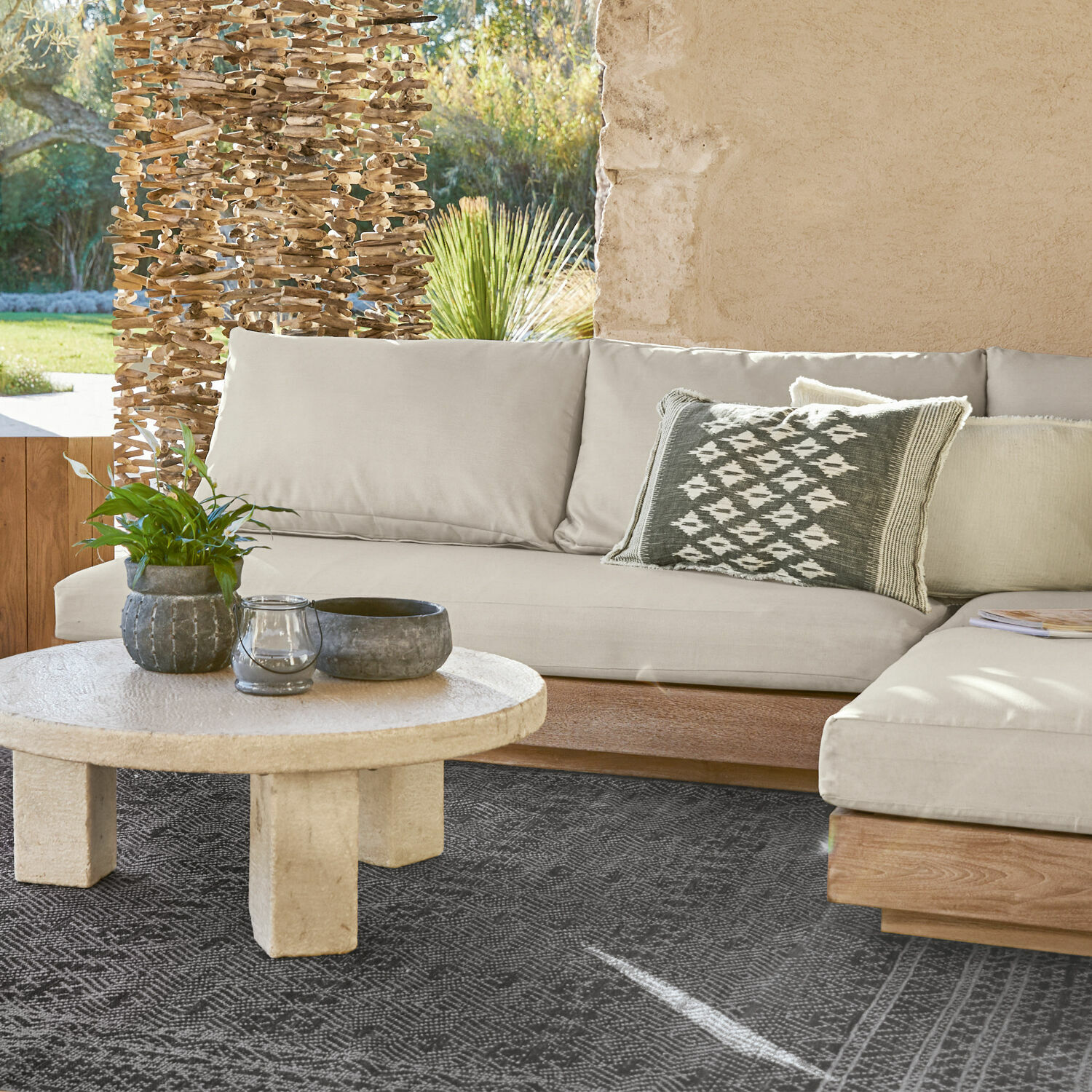 Modulo per divano componibile Courtelevant Divano beige con base in legno e cuscino decorativo su tappeto nero in soggiorno luminoso.