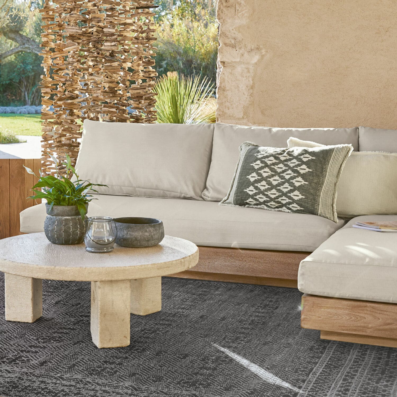 Modulo per divano componibile Courtelevant Divano beige con base in legno e cuscino decorativo su tappeto nero in soggiorno luminoso.