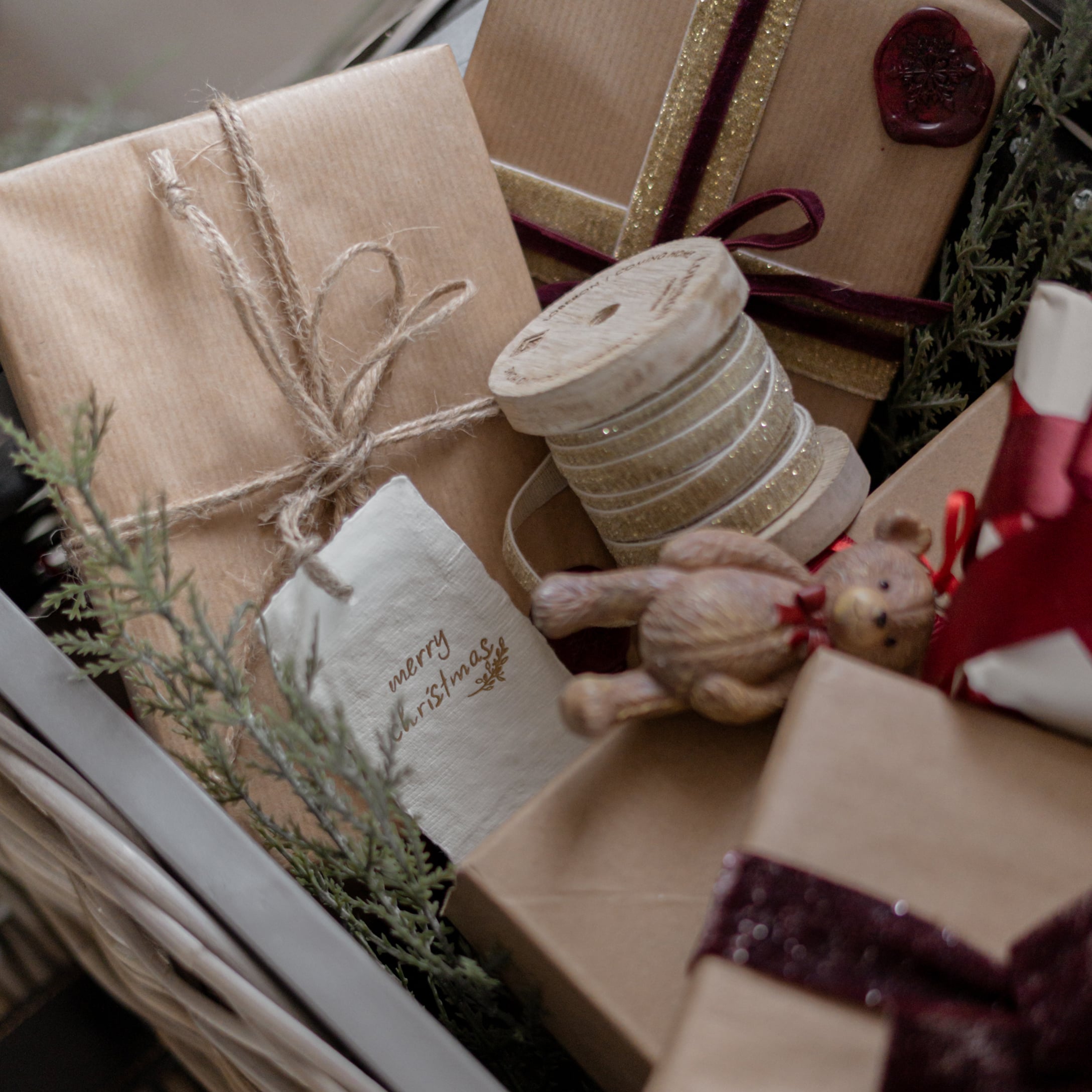 Regali di Natale avvolti in carta marrone con nastro decorativo e orsetto di legno
