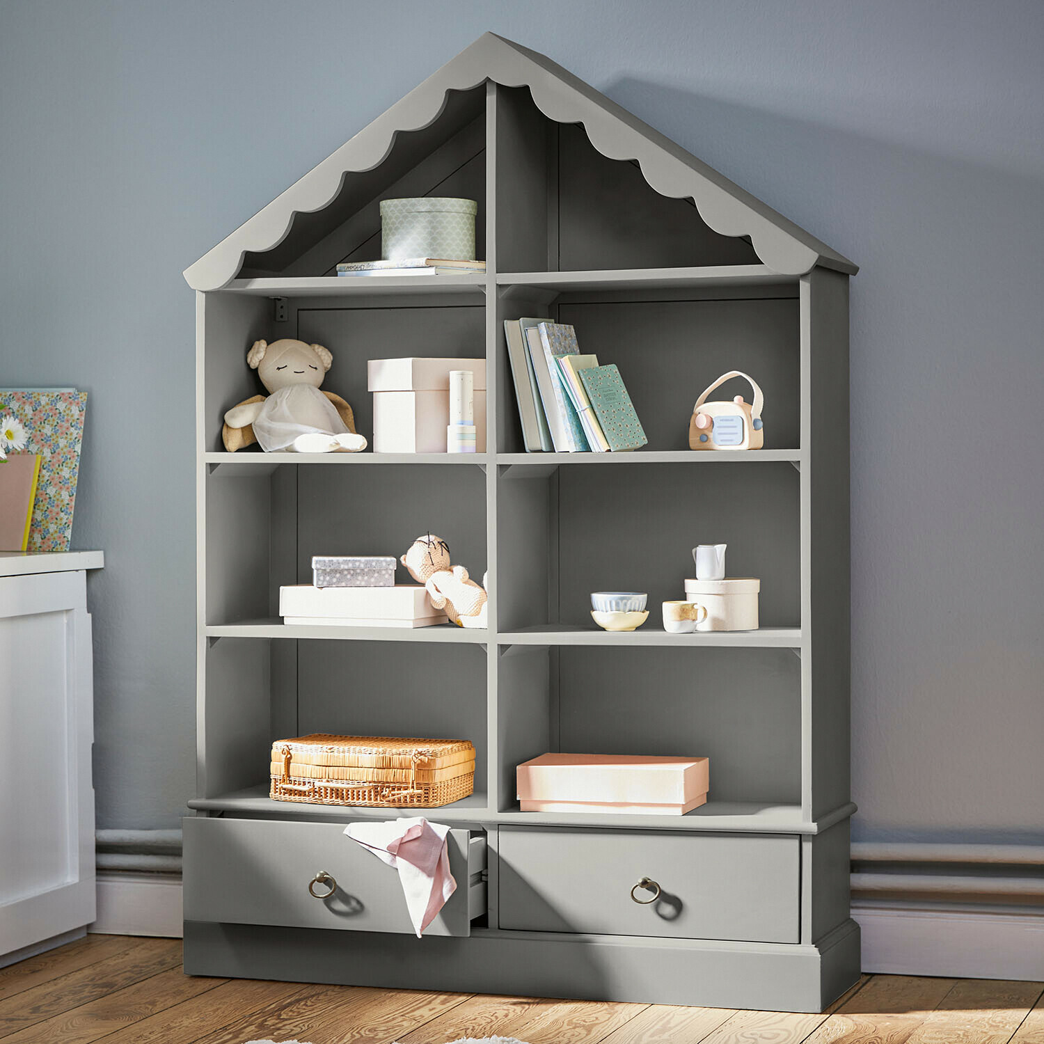Scaffale grigio in legno a forma di casa con giocattoli e libri per cameretta