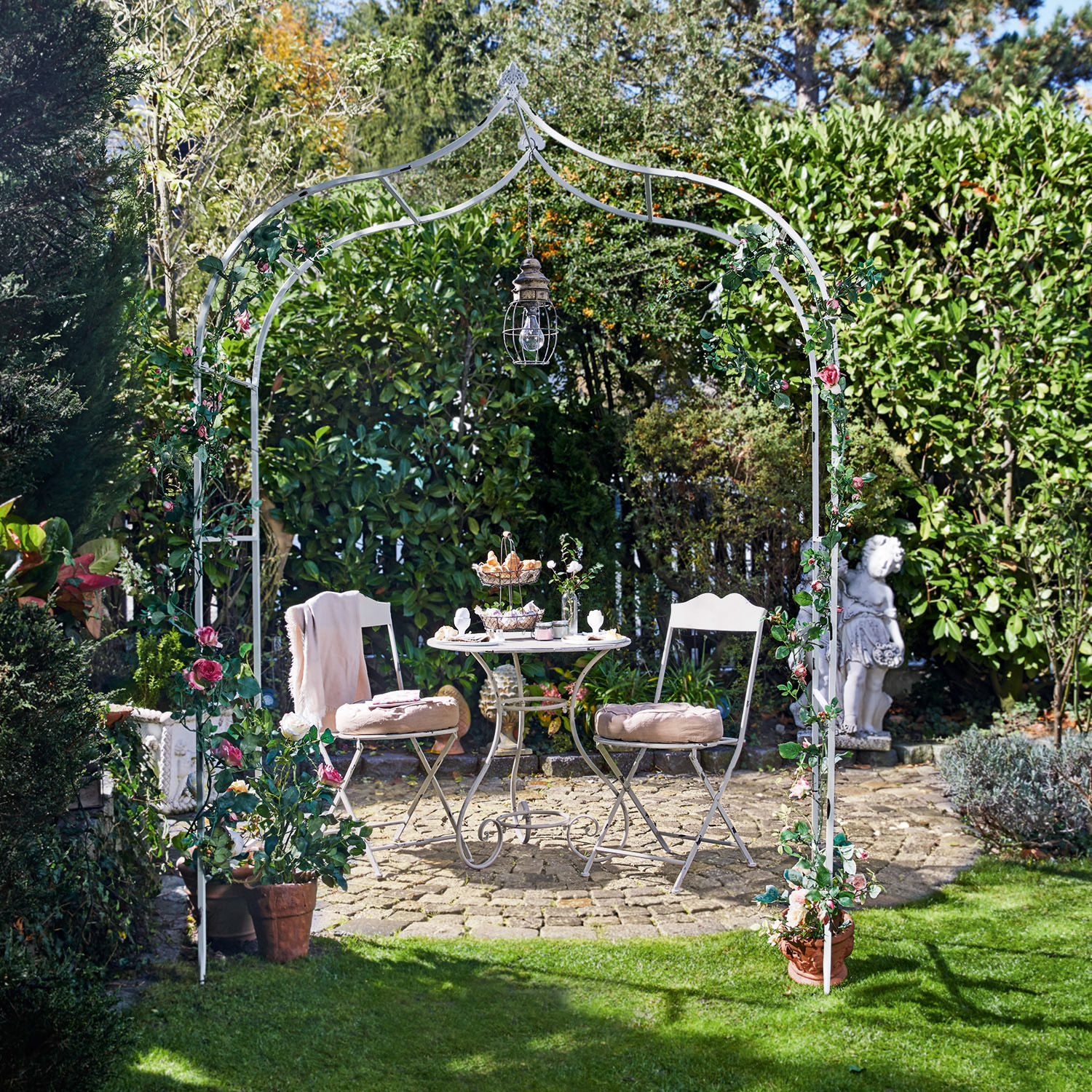 Arco da giardino Dimarus Arco da giardino in metallo bianco con fiori rosa e lampada, tavolo e sedie su patio in pietra