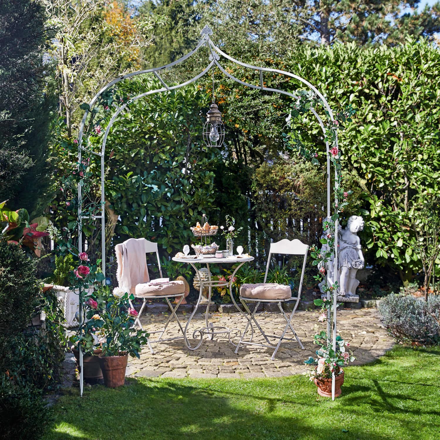 Arco da giardino Dimarus Arco da giardino in metallo bianco con fiori rosa e lampada, tavolo e sedie su patio in pietra