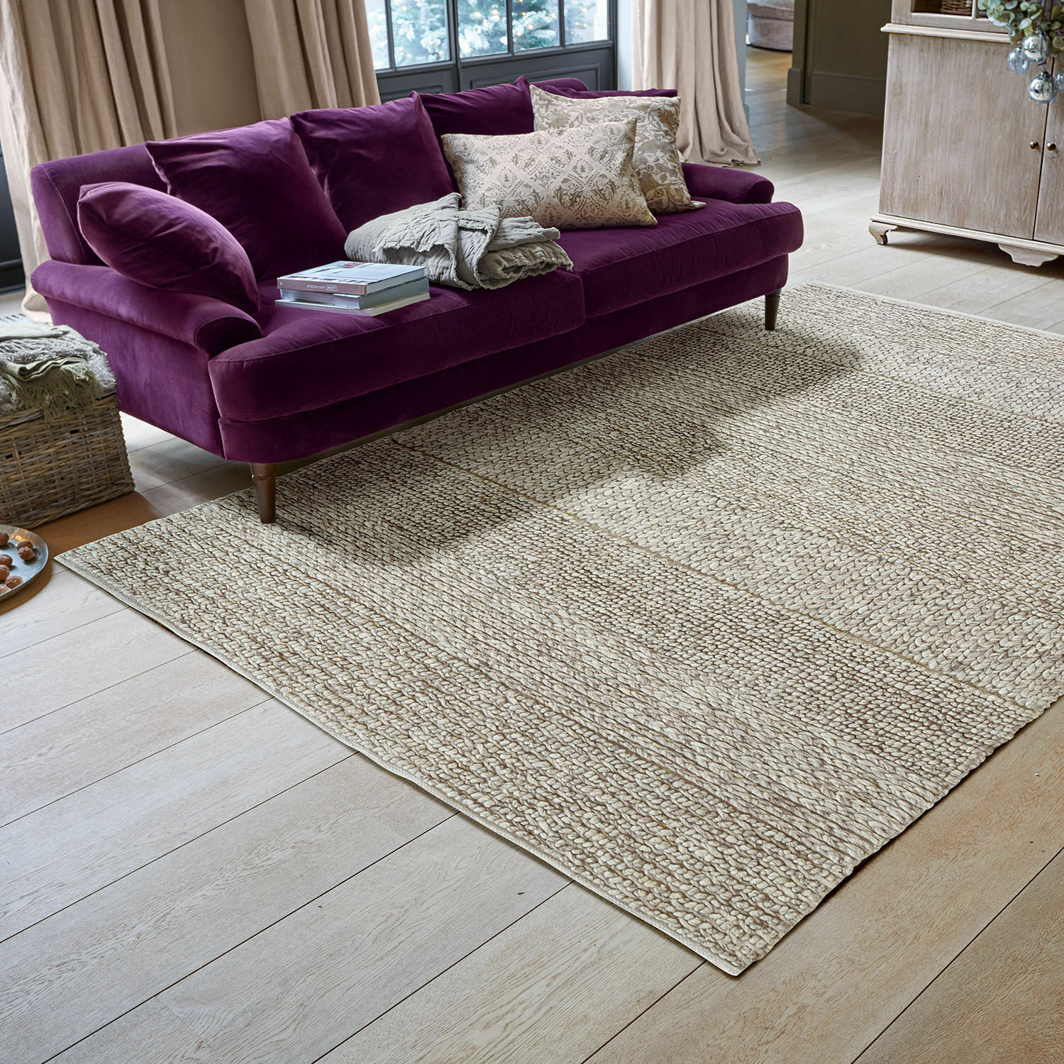 Tappeto Welezas Divano viola in velluto su tappeto beige in materiale naturale in soggiorno luminoso