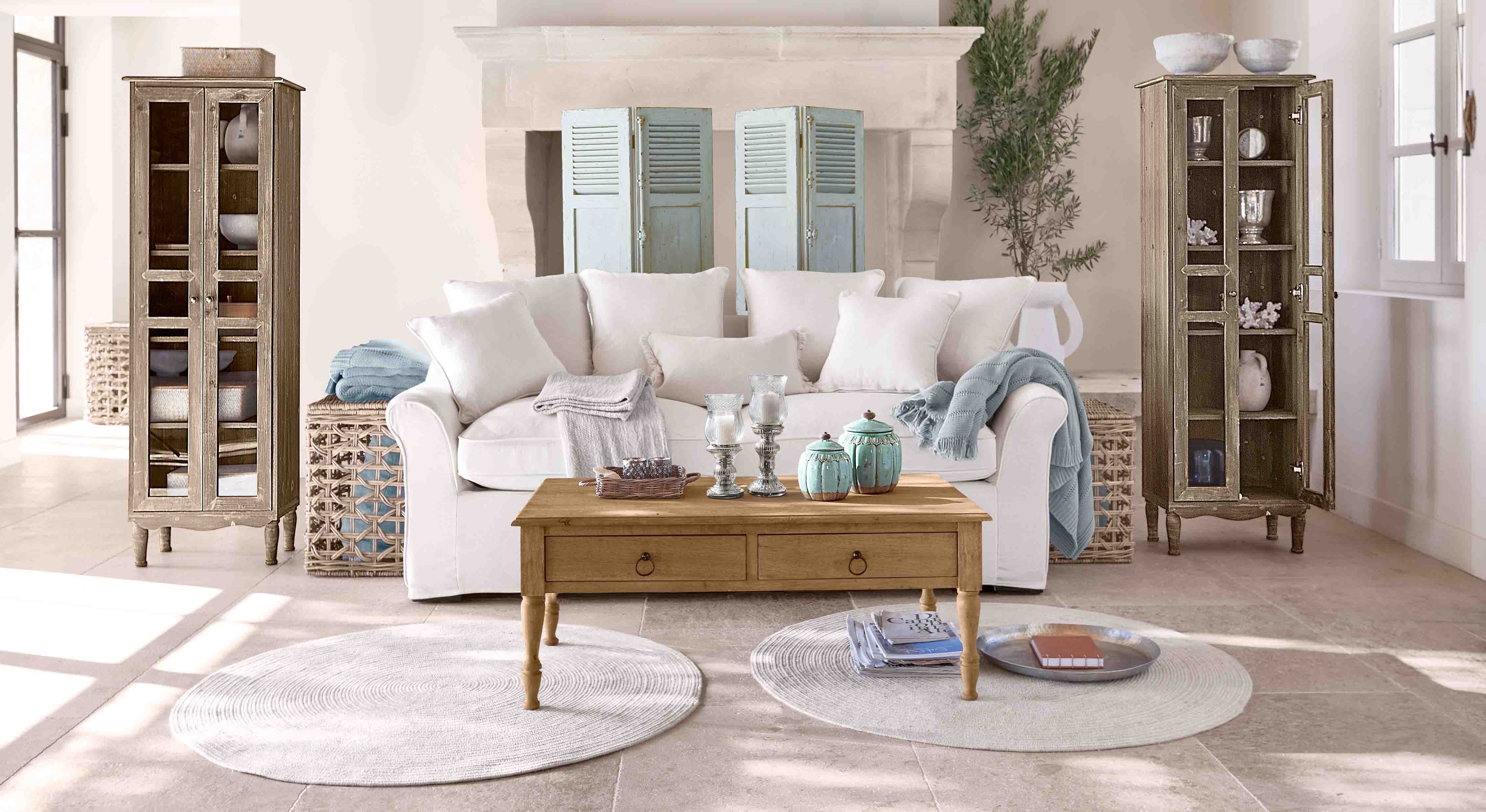 Soggiorno accogliente con divano bianco, tavolino in legno e due vetrine in legno stile vintage