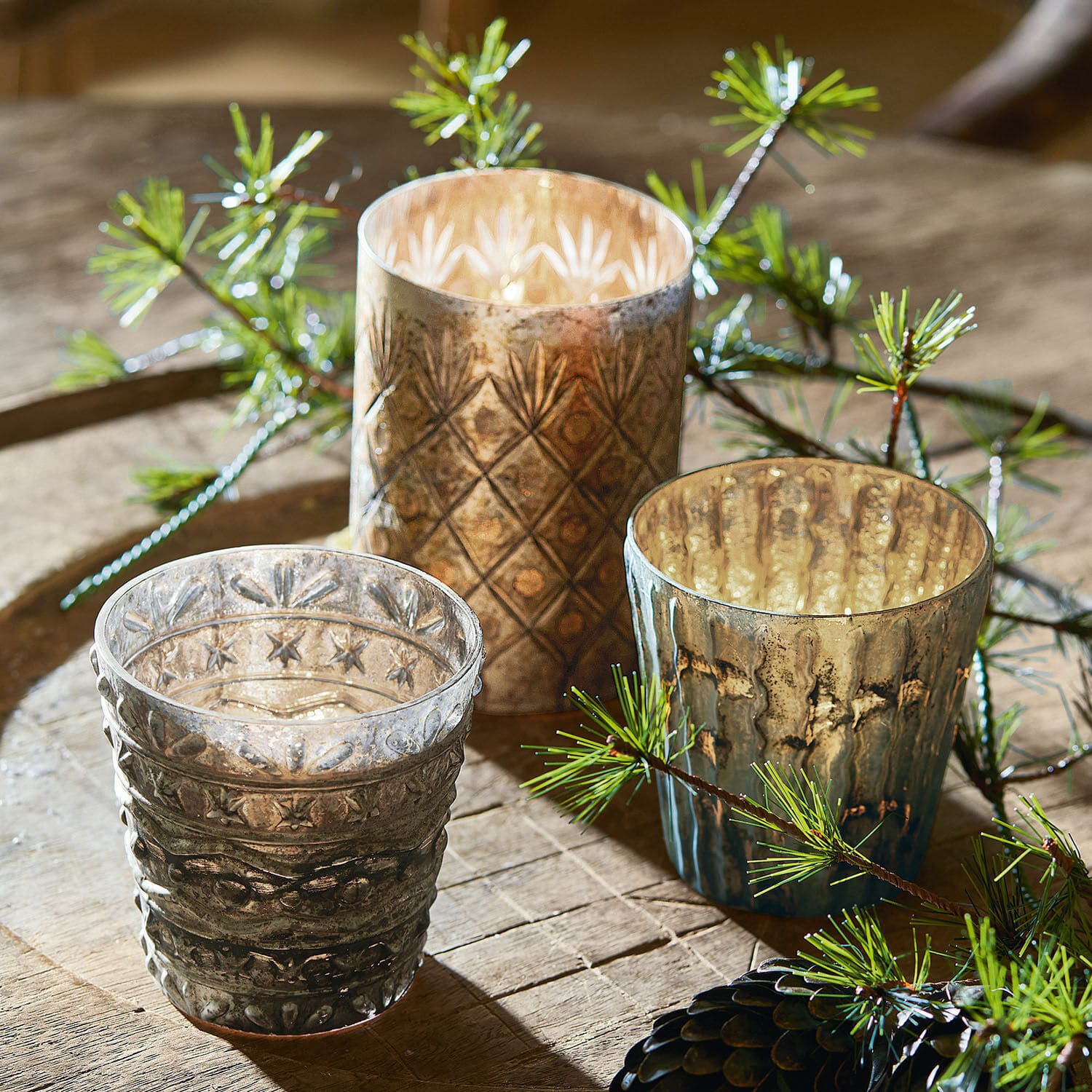 Set di 3 portacandele Ginai Set di tre portacandele in vetro con motivo decorativo in tonalità marroni e grigie su tavolo in legno