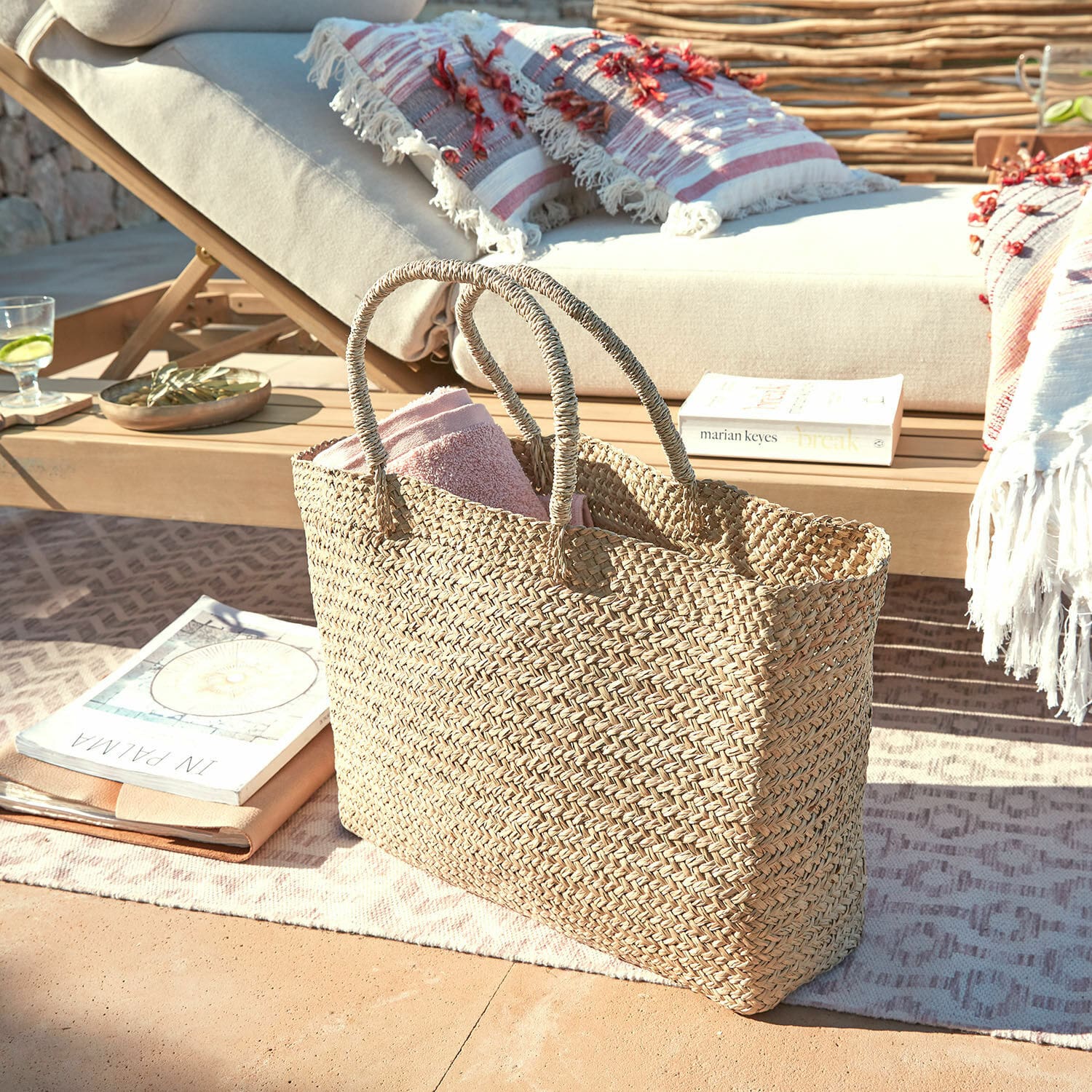 Borsa Ventresque Borsa intrecciata naturale in erba marina con asciugamano rosa su terrazza vicino a lettino
