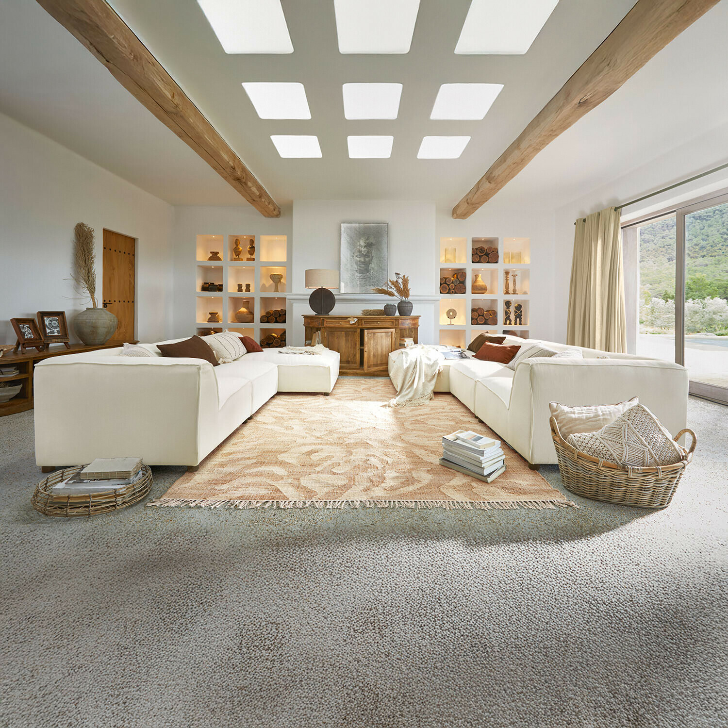 Divano McLean Ampio soggiorno con divano bianco, travi in legno, decorazioni naturali, tappeto beige e grande finestra luminosa