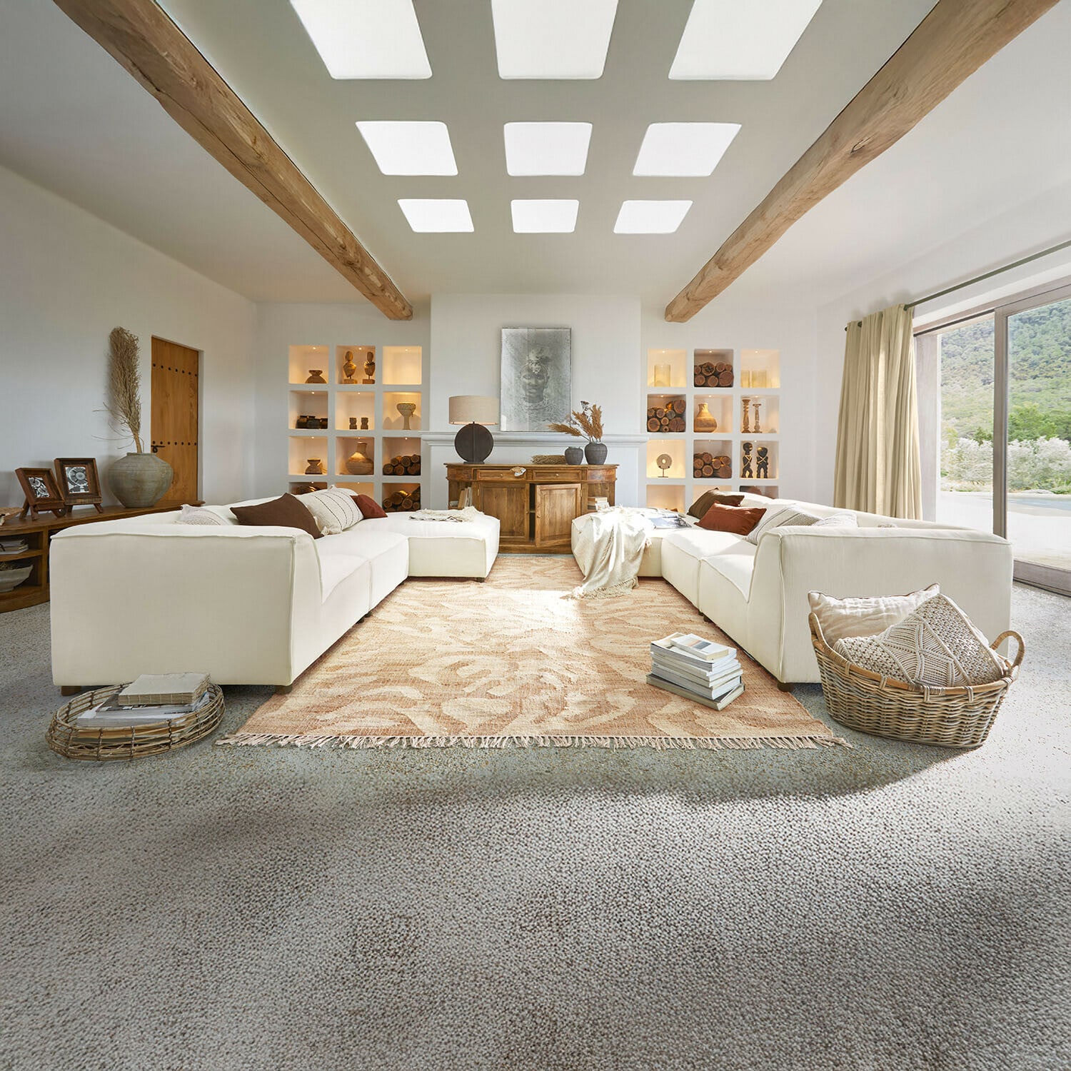Divano McLean Ampio soggiorno con divano bianco, travi in legno, decorazioni naturali, tappeto beige e grande finestra luminosa