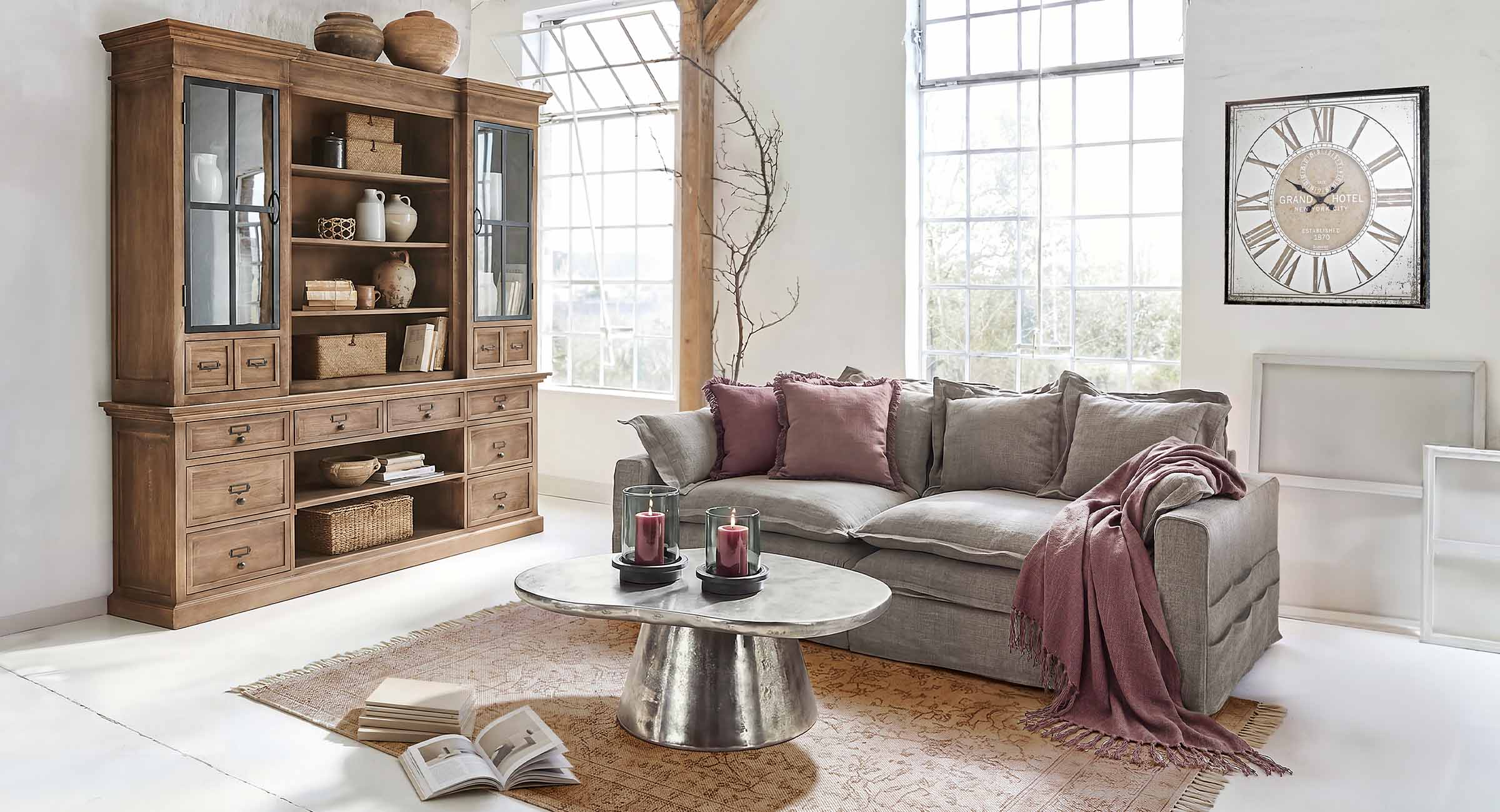 Soggiorno accogliente con divano grigio, cuscini bordeaux e vetrina in legno stile vintage