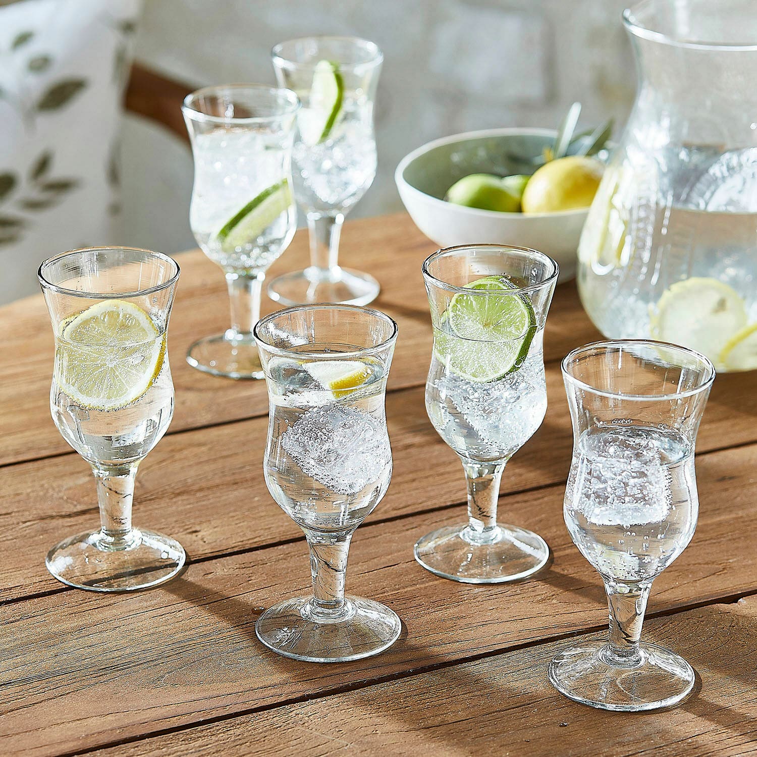 Set di 6 bicchieri Gaëtane Set di sei bicchieri trasparenti con acqua, ghiaccio e fette di limone su tavolo in legno