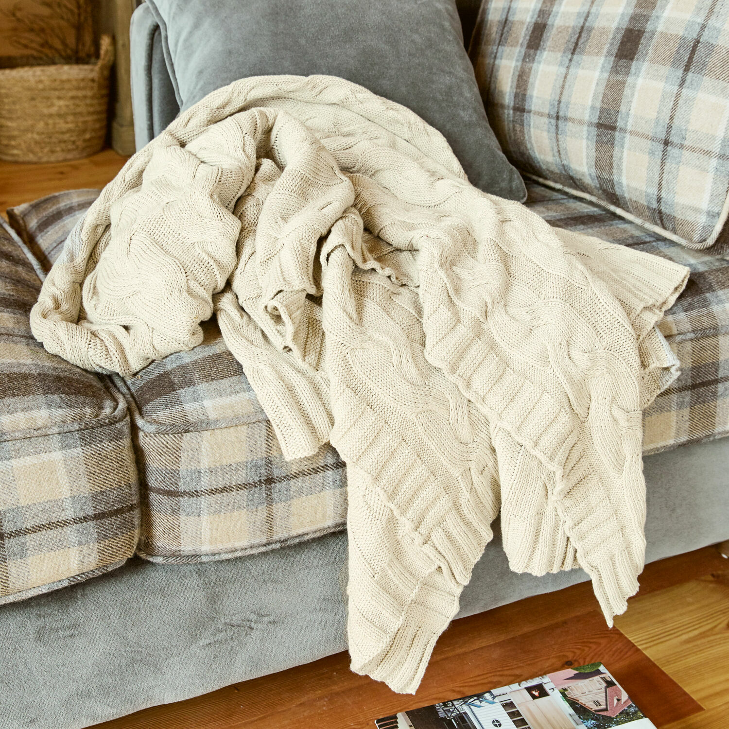 Coperta Arnhem Coperta beige in cotone lavorata a maglia su divano grigio a quadri beige in soggiorno