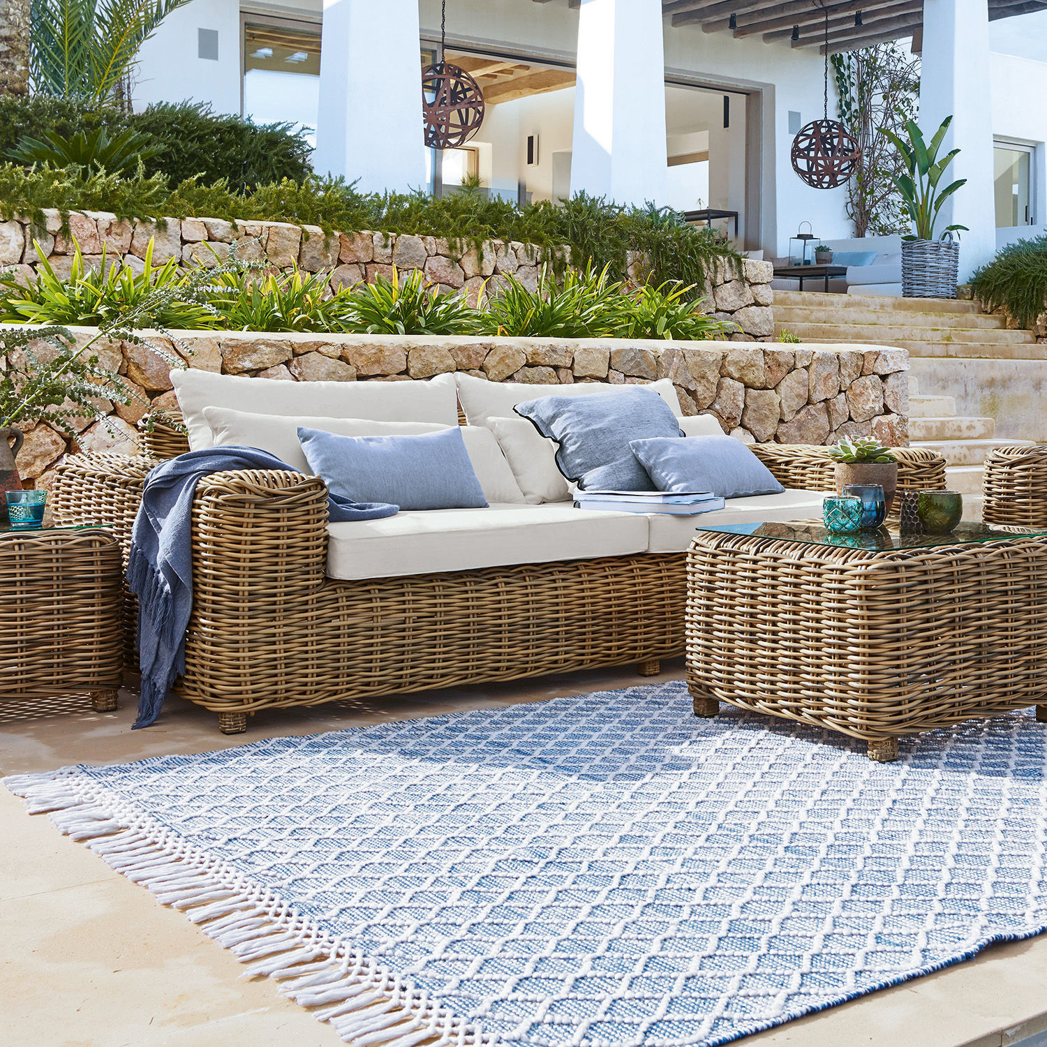 Divano Camas Set di mobili da giardino in rattan naturale con cuscini crema e tappeto blu a motivo