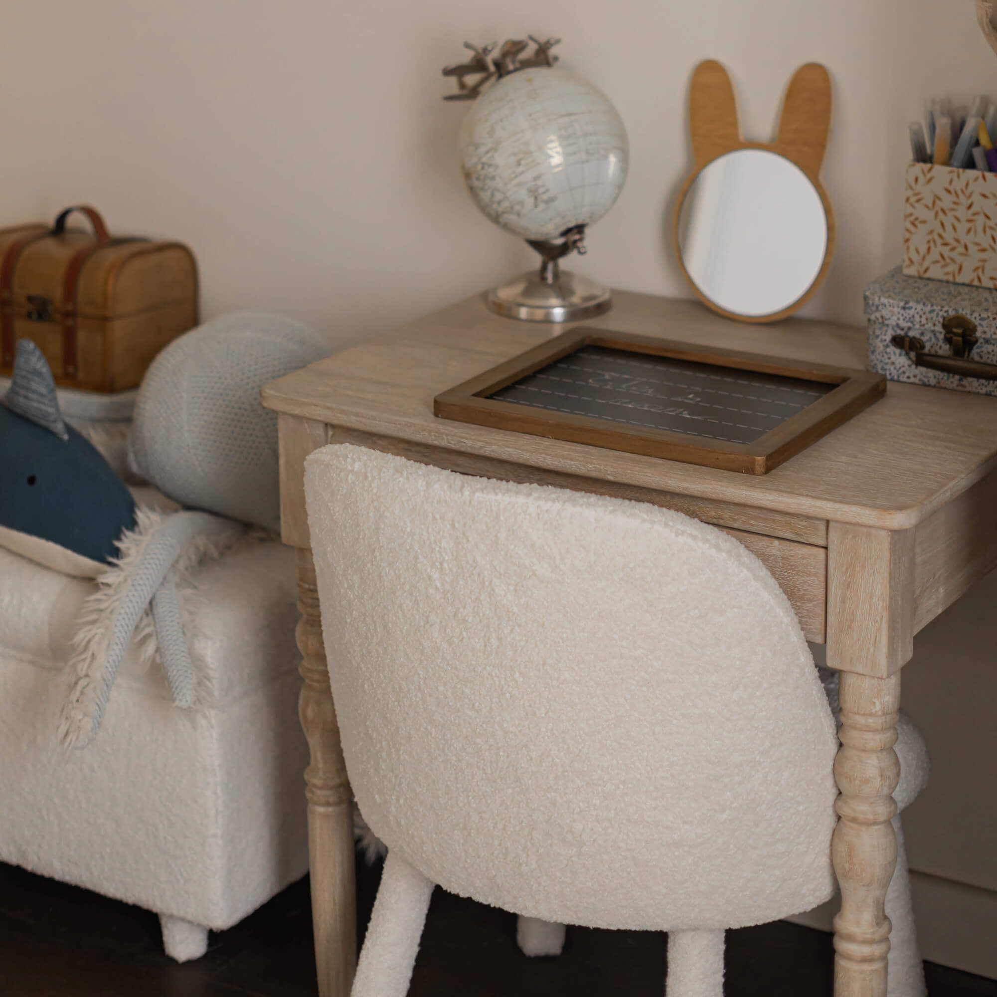 Scrivania in legno chiaro con sedia beige in tessuto morbido in una cameretta accogliente