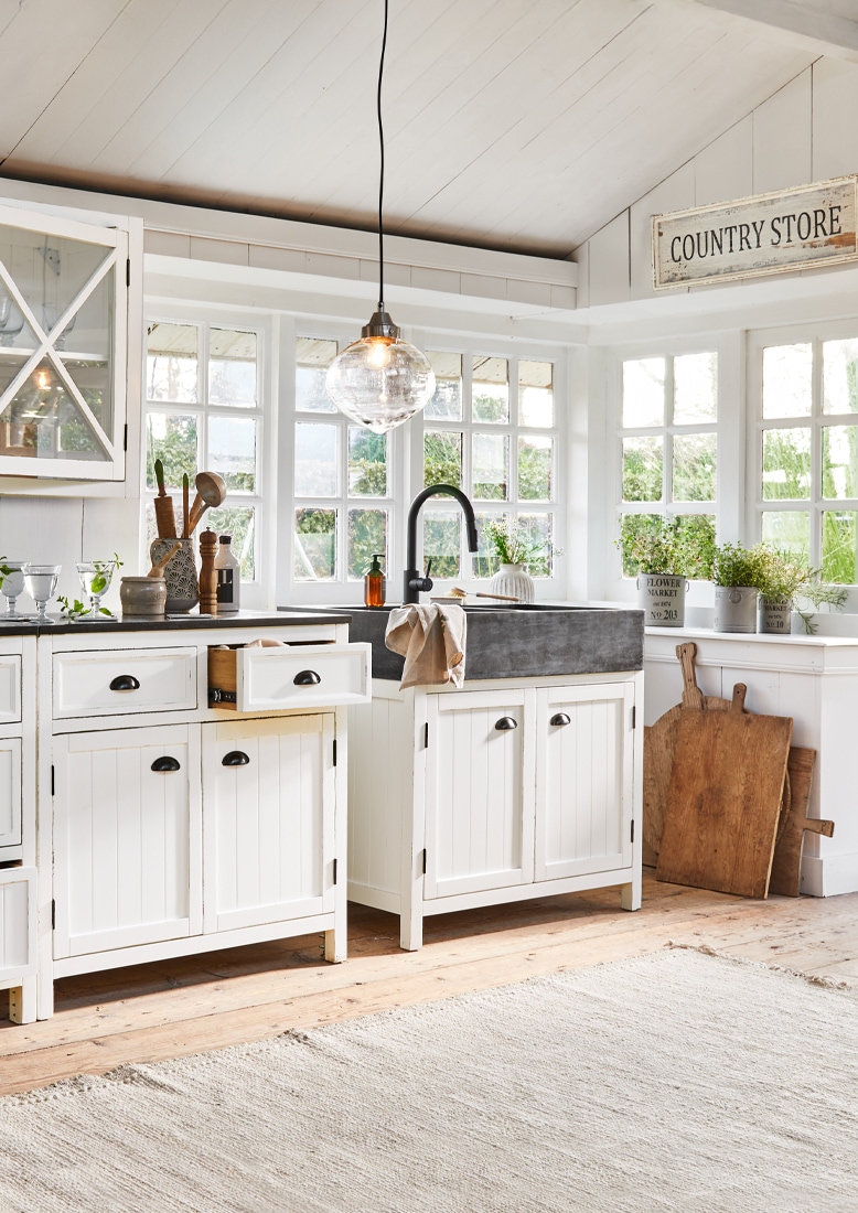 Cucina in stile country con mobili bianchi in legno e lavello nero in pietra, decorazioni vegetali