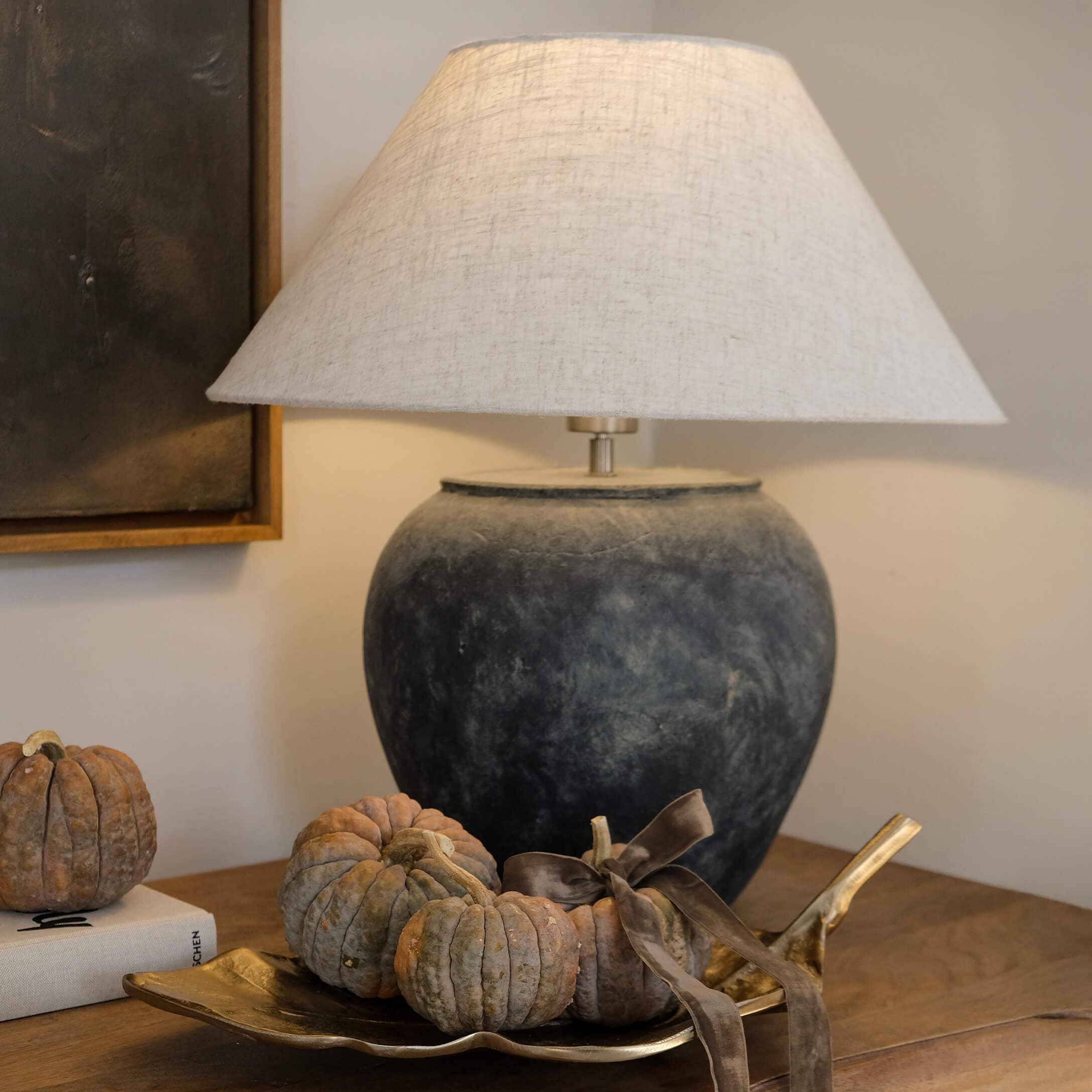 Lampada da tavolo in ceramica grigio scuro con paralume beige e decorazione di piccole zucche su vassoio dorato