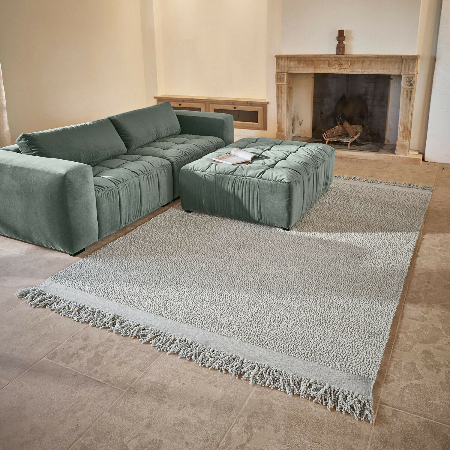 Tappeto Linnet Divano e pouf verde menta in tessuto morbido su tappeto chiaro con frange in soggiorno con camino