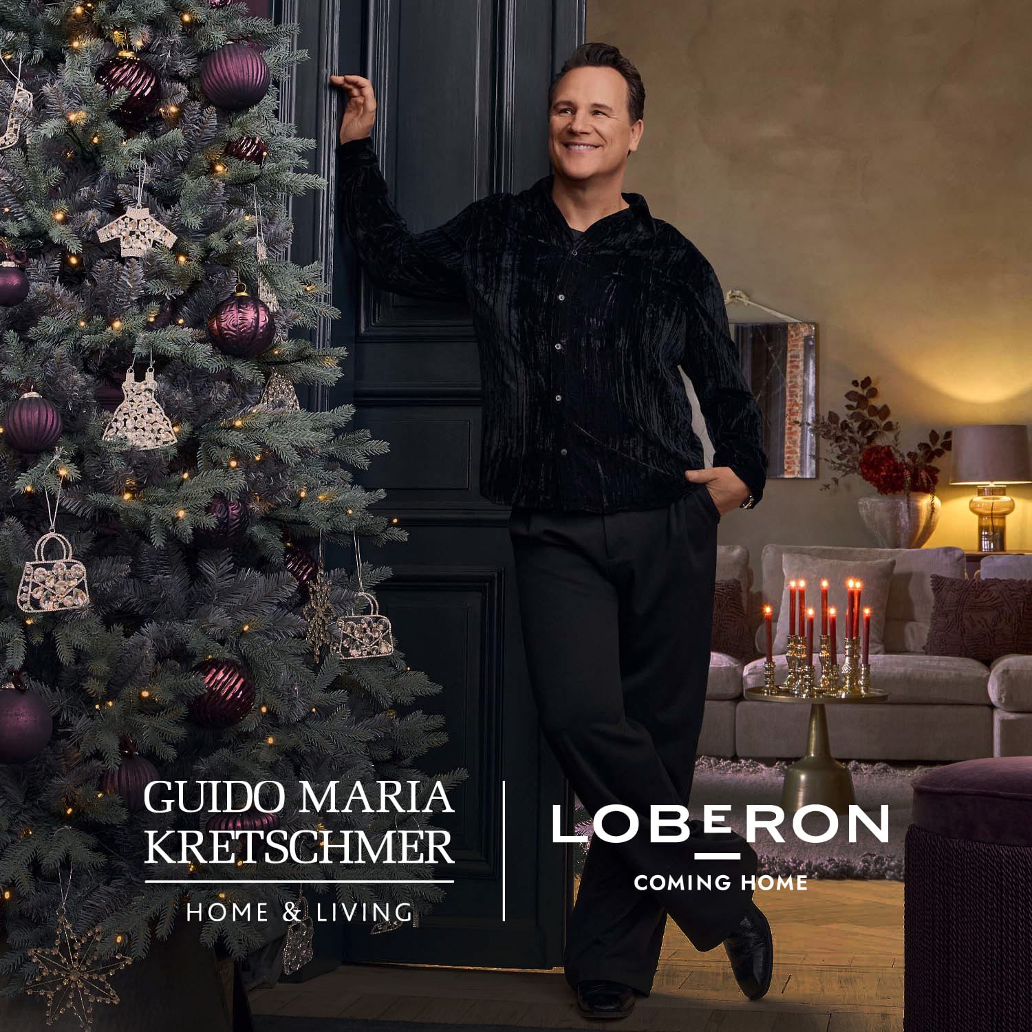 Uomo con camicia nera accanto a un albero di Natale decorato con palline viola e ornamenti dorati