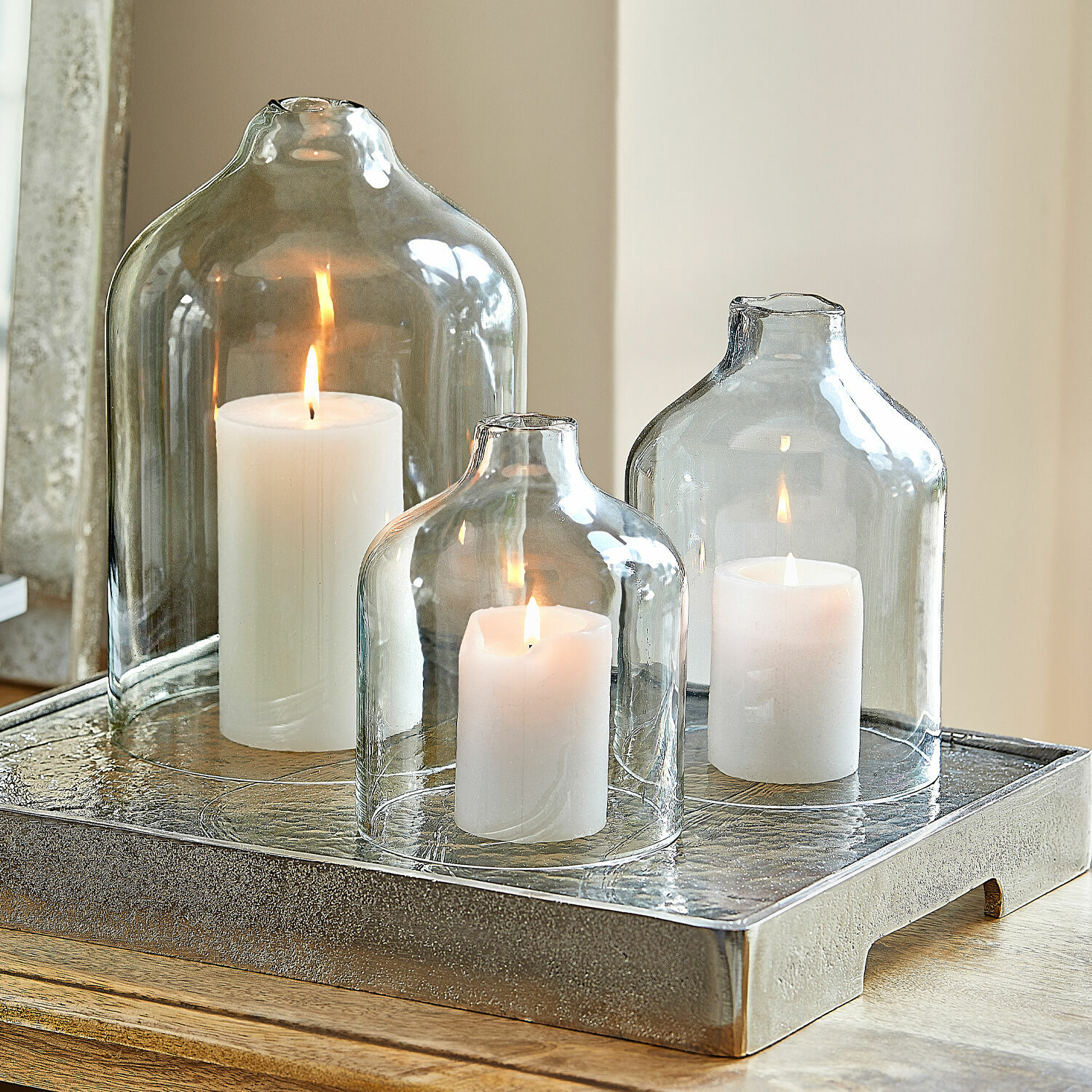 Set di 4 candele Braga Tre candele bianche sotto campane di vetro trasparente su un vassoio decorativo in metallo