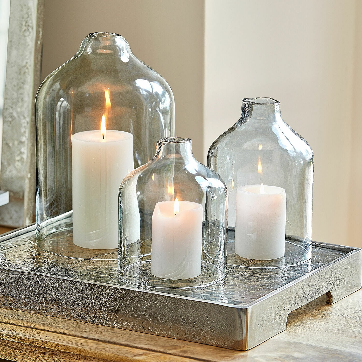 Set di 4 candele Braga Tre candele bianche sotto campane di vetro trasparente su un vassoio decorativo in metallo