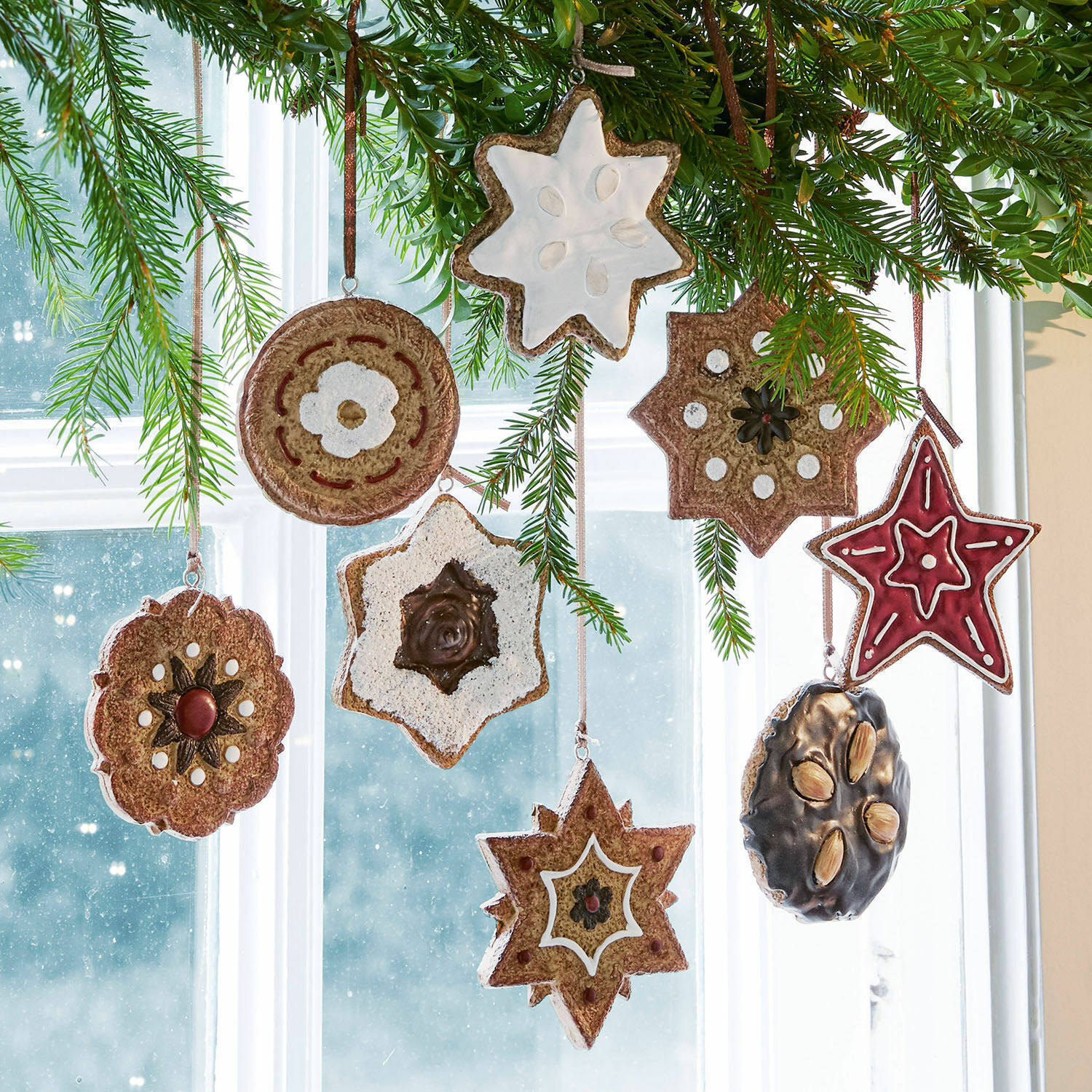 Set di 8 decorazioni da appendere Cibla Decorazioni natalizie a forma di stelle e cerchi in materiali naturali appese davanti a una finestra