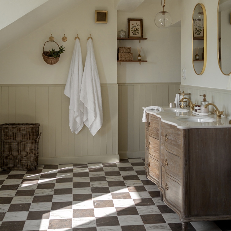Bagno con pavimento a scacchi in marmo, mobile in legno e asciugamani bianchi appesi