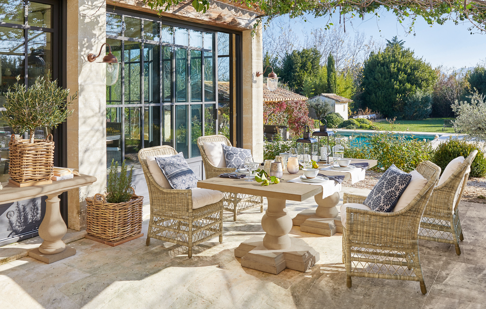 Accogliente terrazza con mobili in rattan e tavolo in pietra in stile mediterraneo con vista piscina