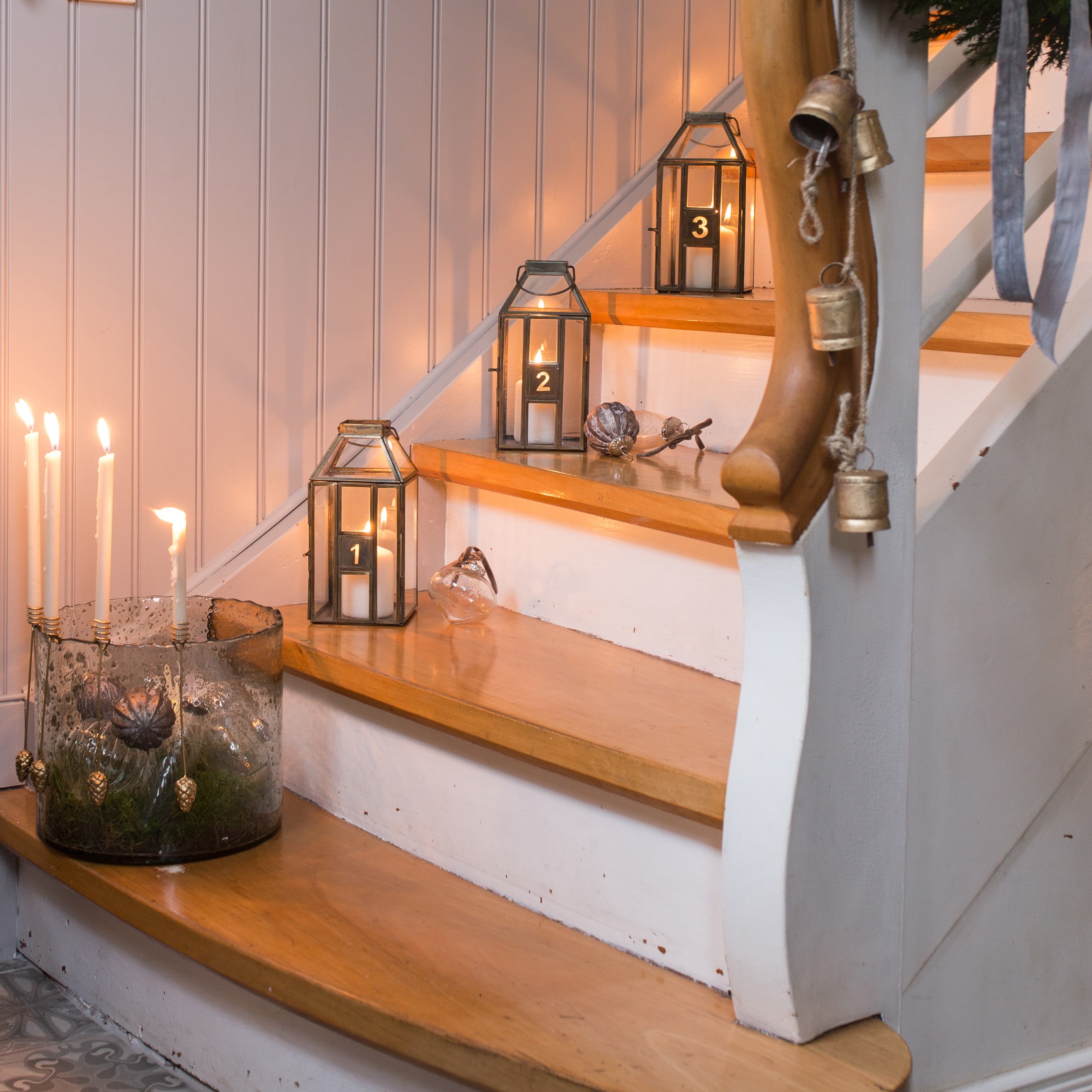 Lanternine di vetro numerate con candele bianche su scale in legno in stile vintage