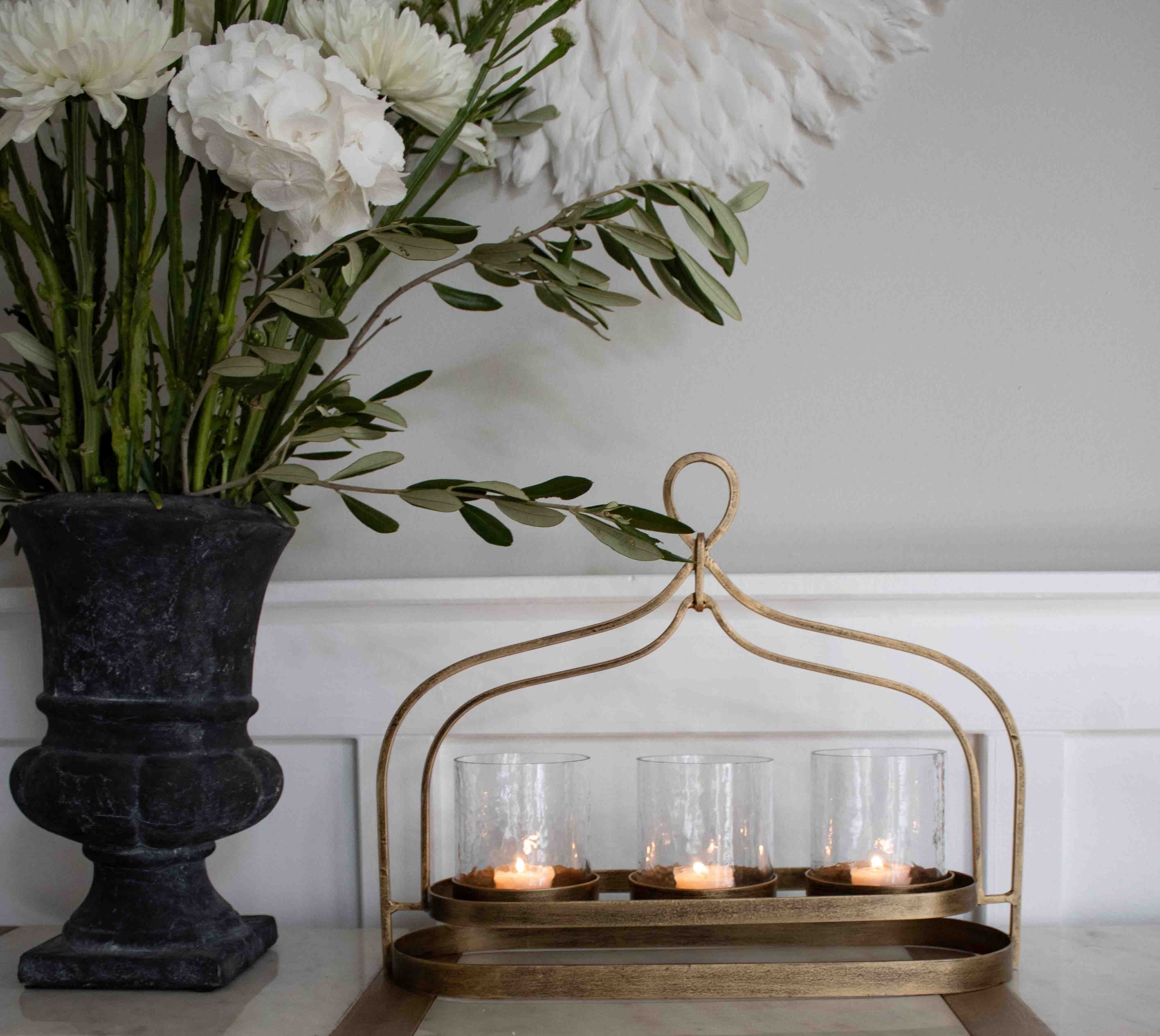 Portacandele in metallo dorato con tre bicchieri di vetro per tealight su tavolo decorativo