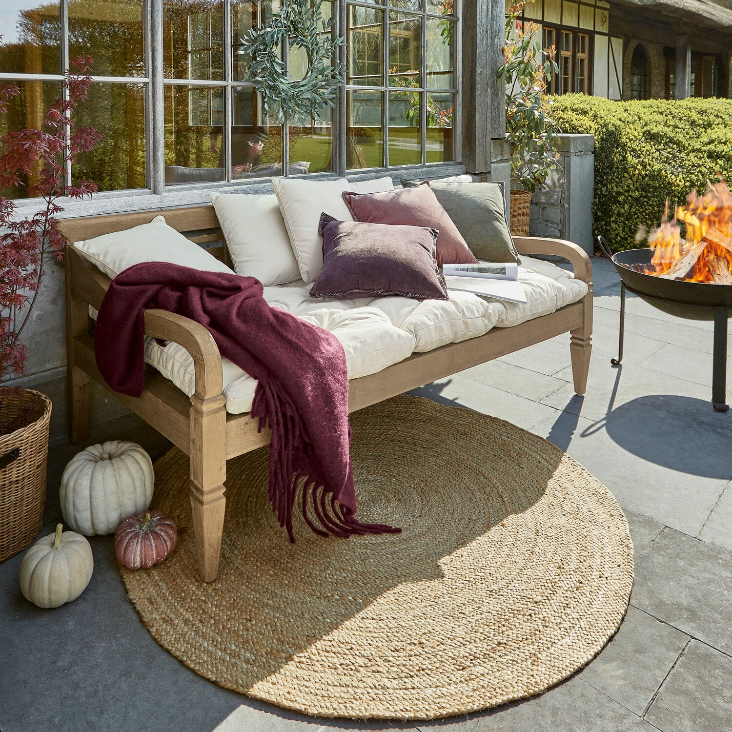 Panca Fairwood Panca da giardino in legno con cuscini crema e coperta bordeaux su terrazza con tappeto in juta
