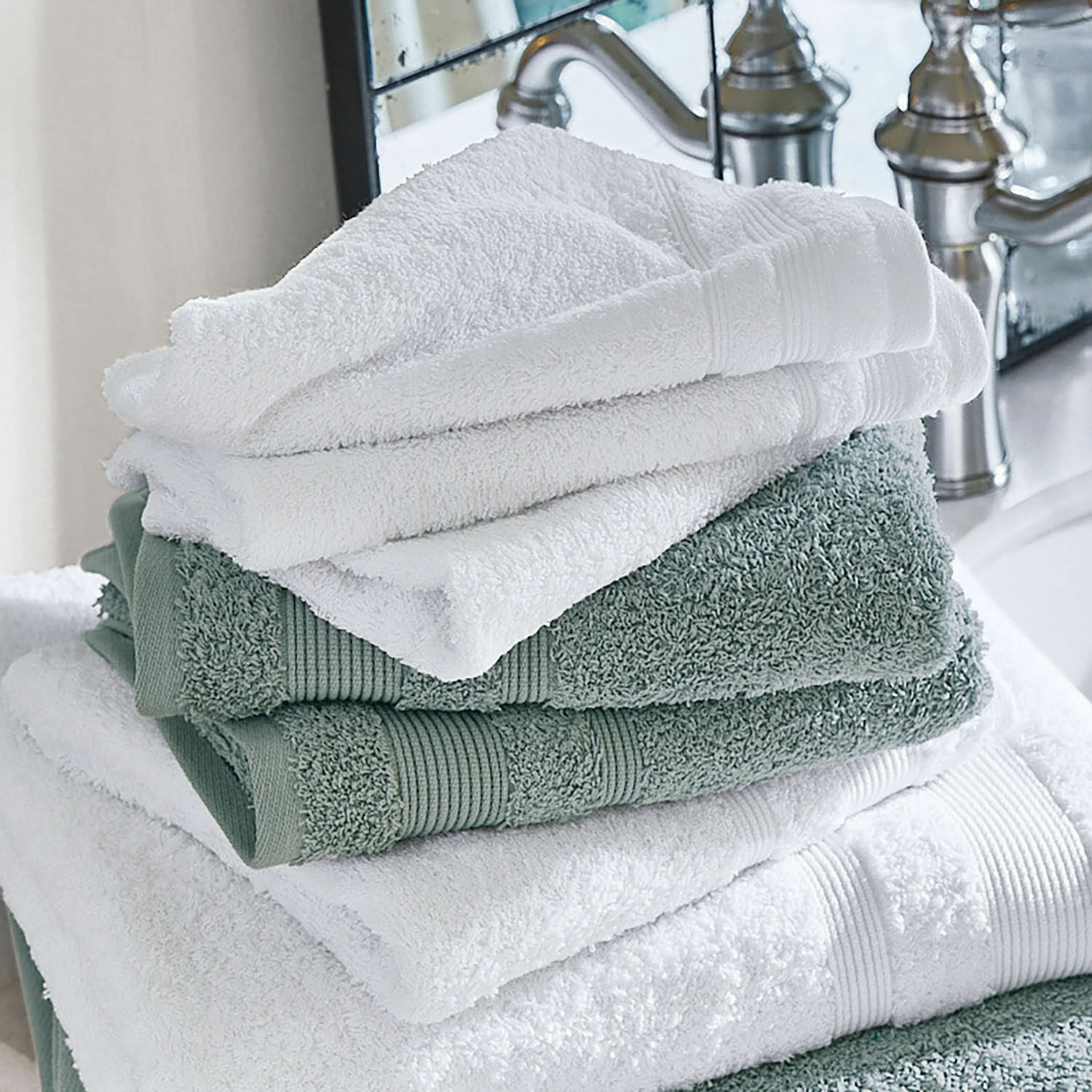 Set di 4 asciugamani Bourogne Morbidi asciugamani di cotone bianchi e verdi impilati in bagno vicino a un rubinetto