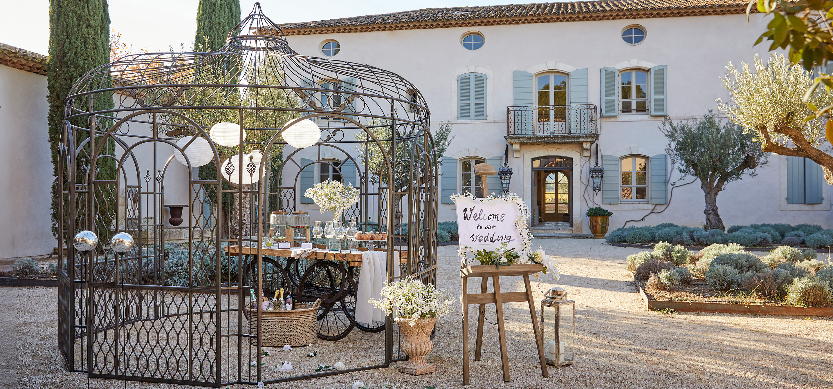 Gazebo da giardino in metallo con motivo decorativo e lanterne, allestito per una festa di matrimonio all'aperto