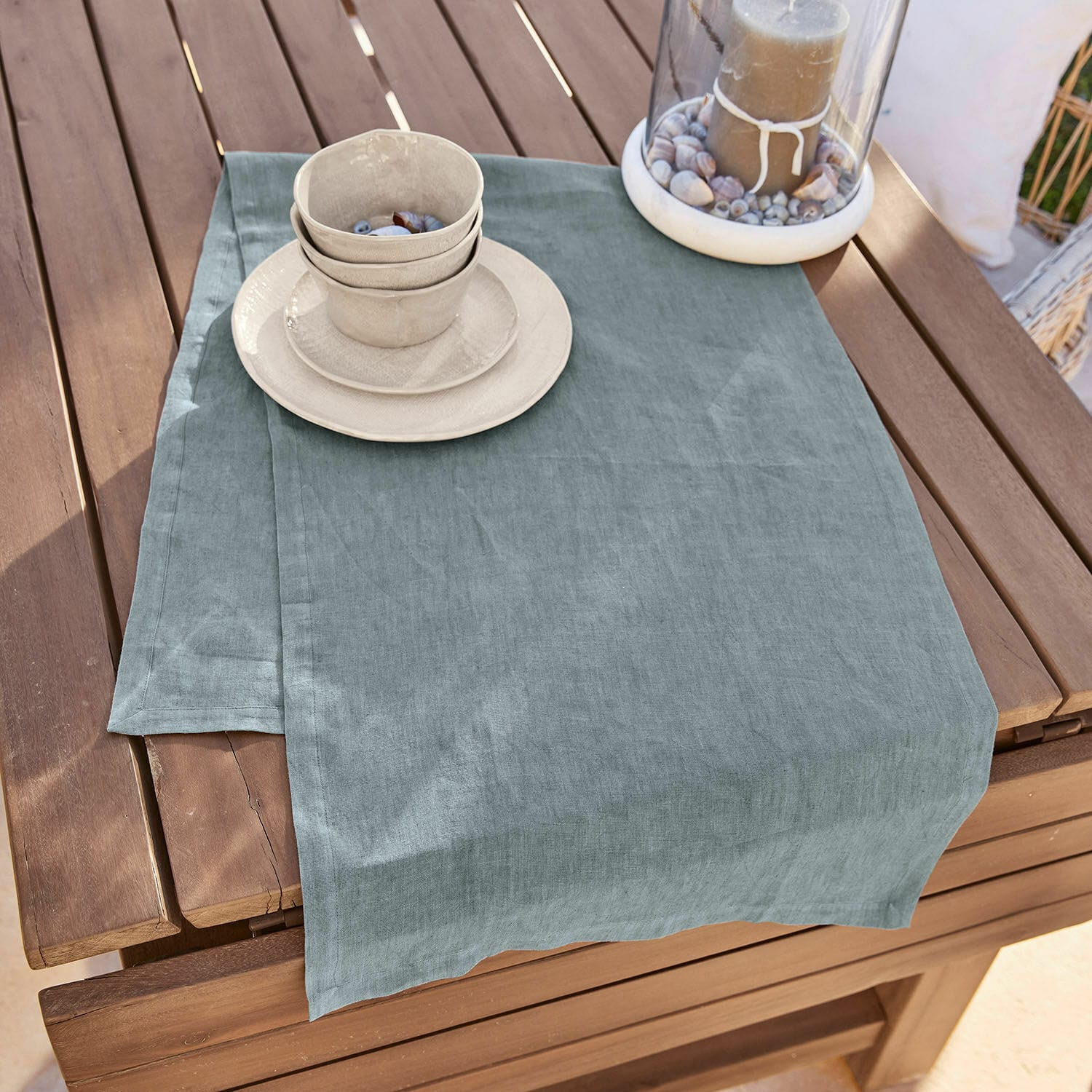 Runner Bursinel Runner da tavola in lino blu-grigio su tavolo in legno con ciotole in ceramica e portacandele