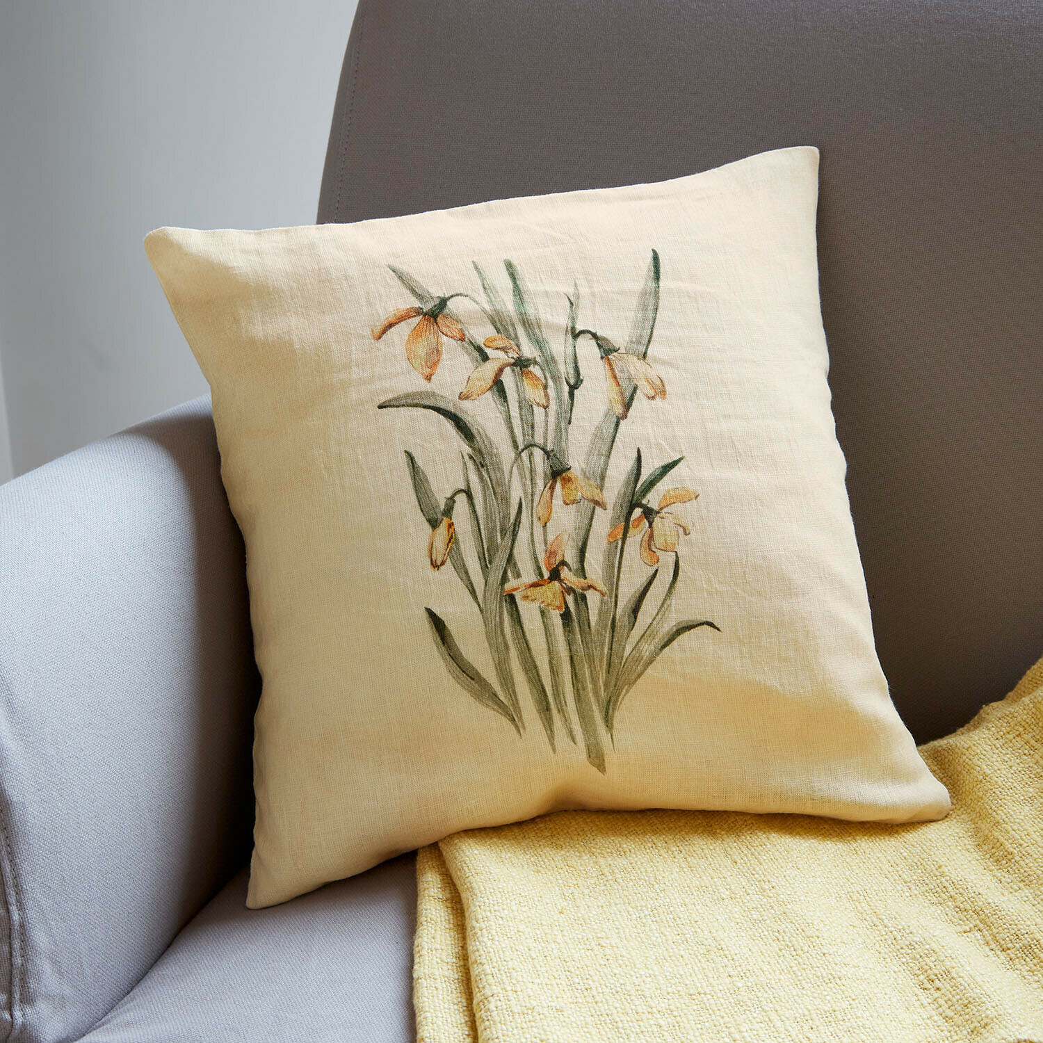Copricuscino Lozere Cuscino in lino beige con stampa floreale gialla su divano grigio con coperta gialla