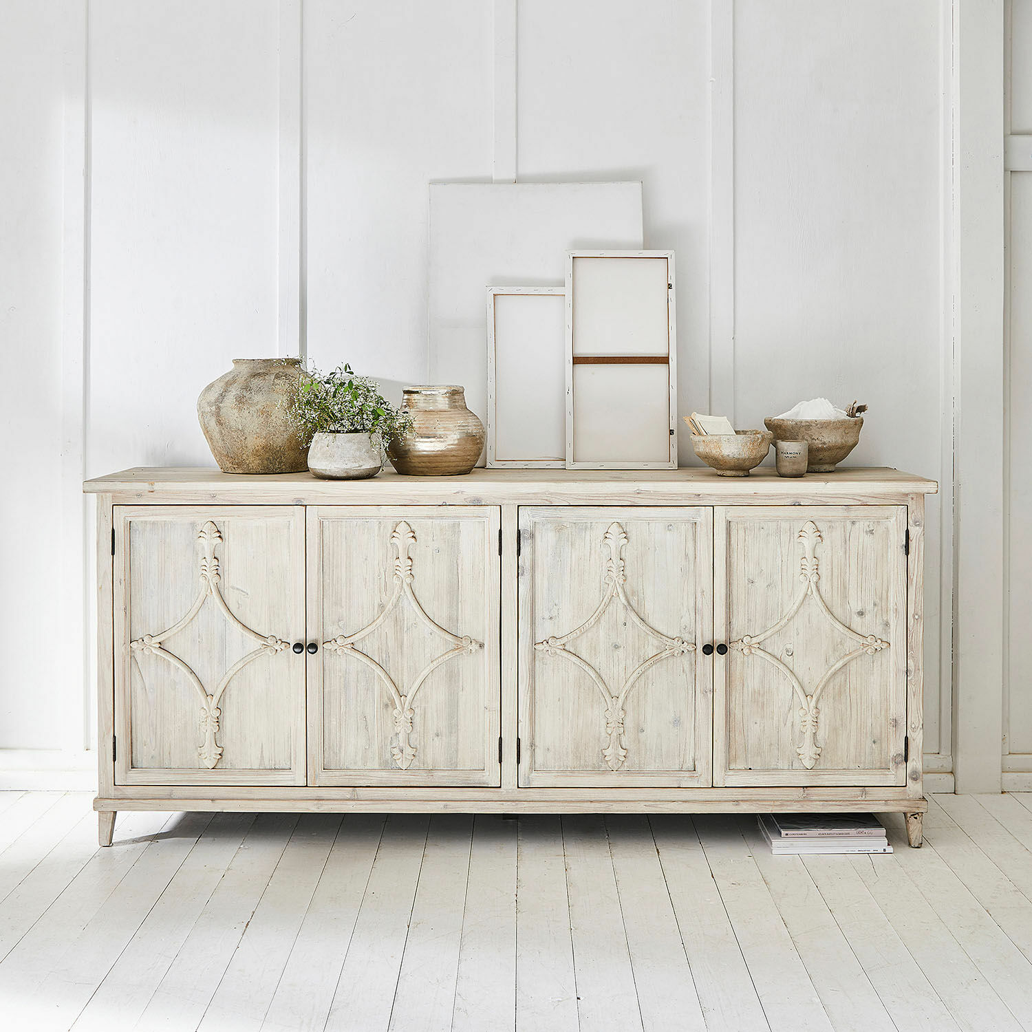 Mobile basso Pemberton Credenza in legno chiaro con ante decorate e vasi in ceramica sopra in ambiente luminoso
