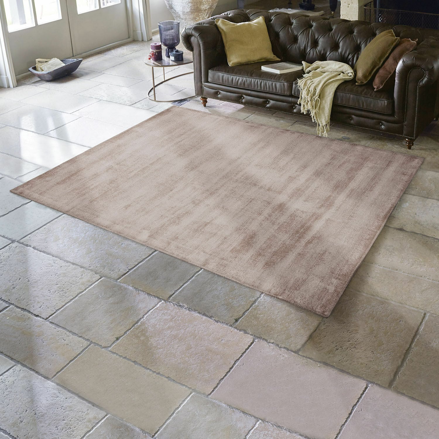 Tappeto Mariselle Tappeto beige in materiale morbido su pavimento in pietra in soggiorno con divano in pelle marrone