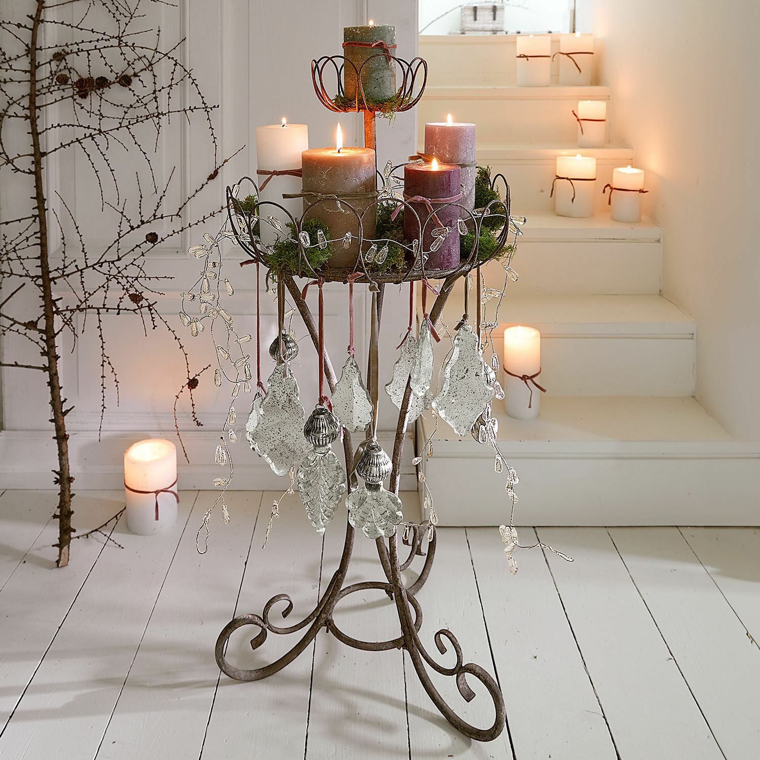 Supporto per decorazioni Mélissant Supporto in metallo con decorazioni e candele in colori naturali su pavimento e scale bianchi
