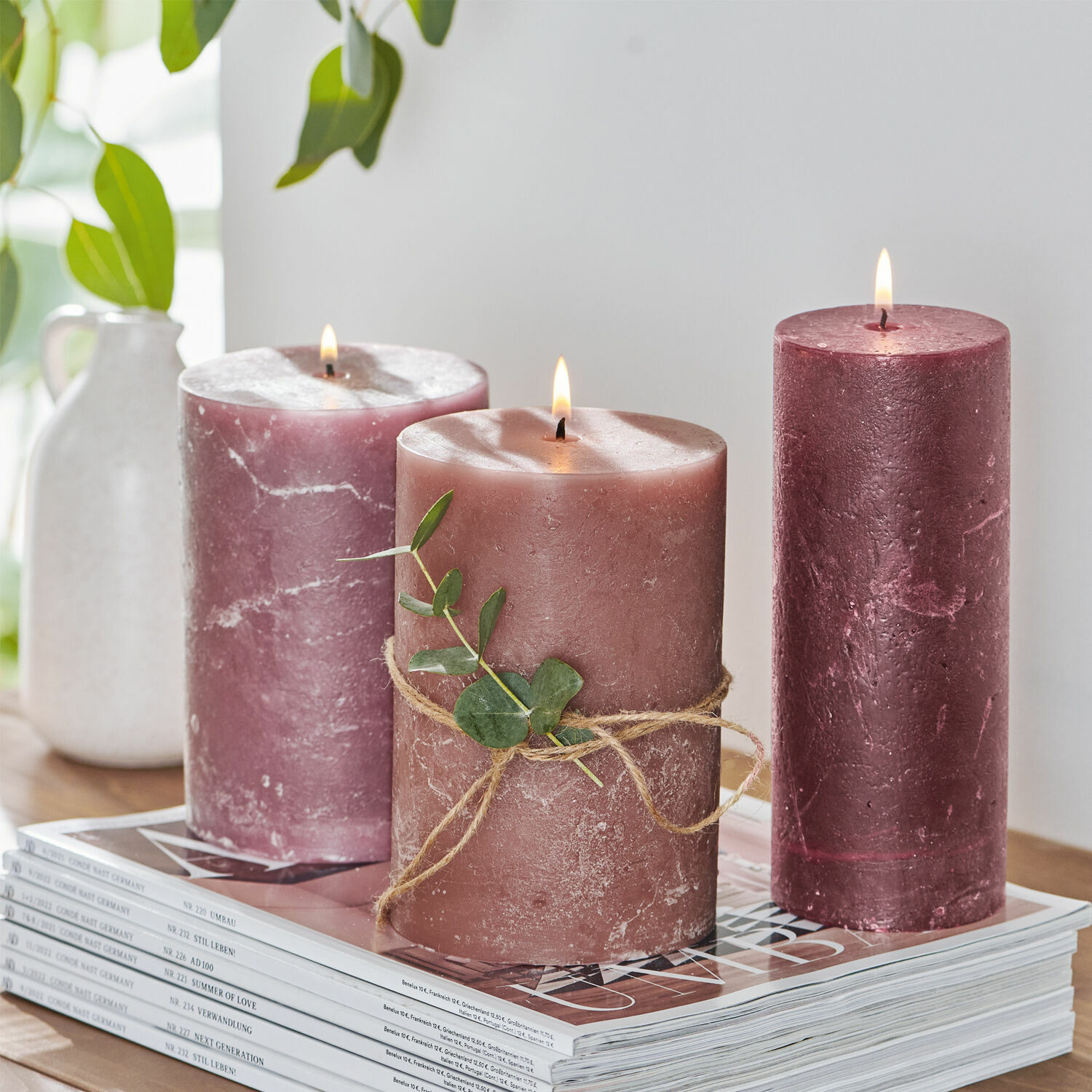 Set di 3 candele Salis Tre candele rosa di cera con foglia verde su una pila di riviste, decorazione per interni