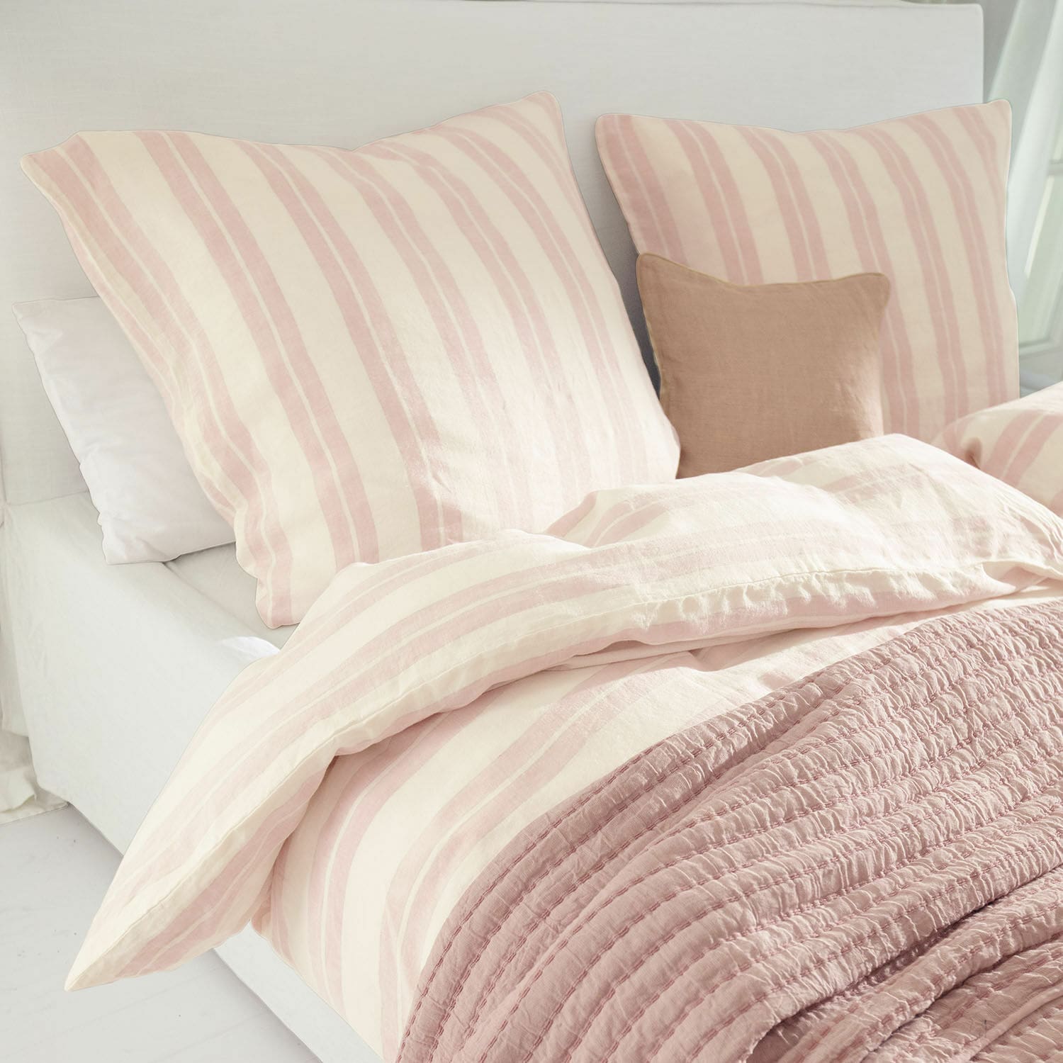 Biancheria da letto Dordogne Biancheria da letto in cotone a righe rosa e crema con coperta rosa morbida su letto chiaro