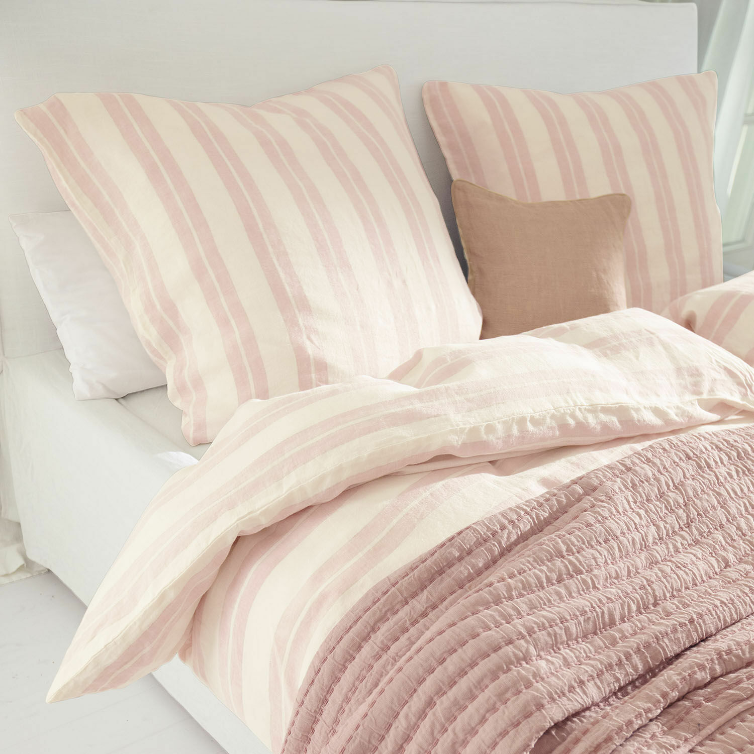 Biancheria da letto Dordogne Biancheria da letto in cotone a righe rosa e crema con coperta rosa morbida su letto chiaro