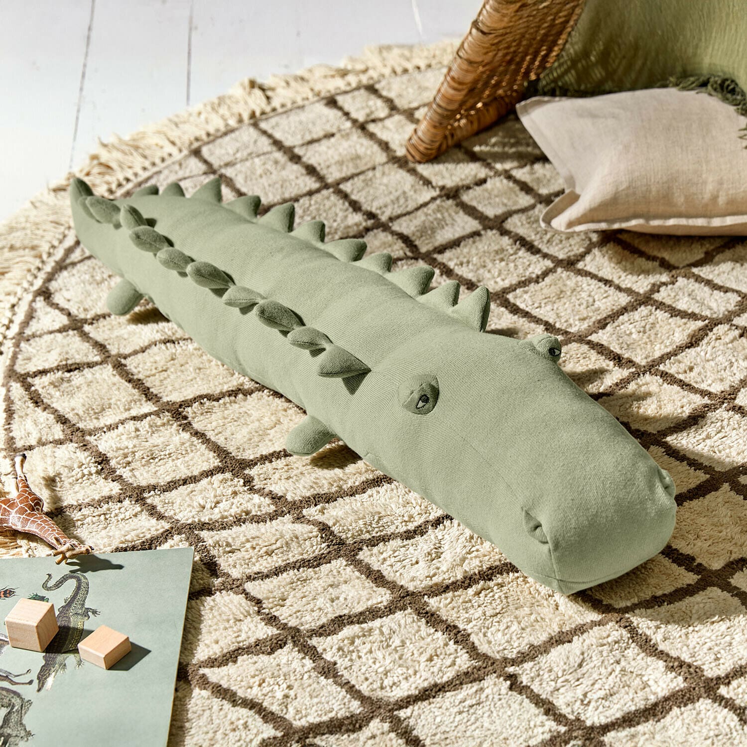 Peluche Zimpy Cuscino morbido verde a forma di coccodrillo su tappeto beige con motivo geometrico