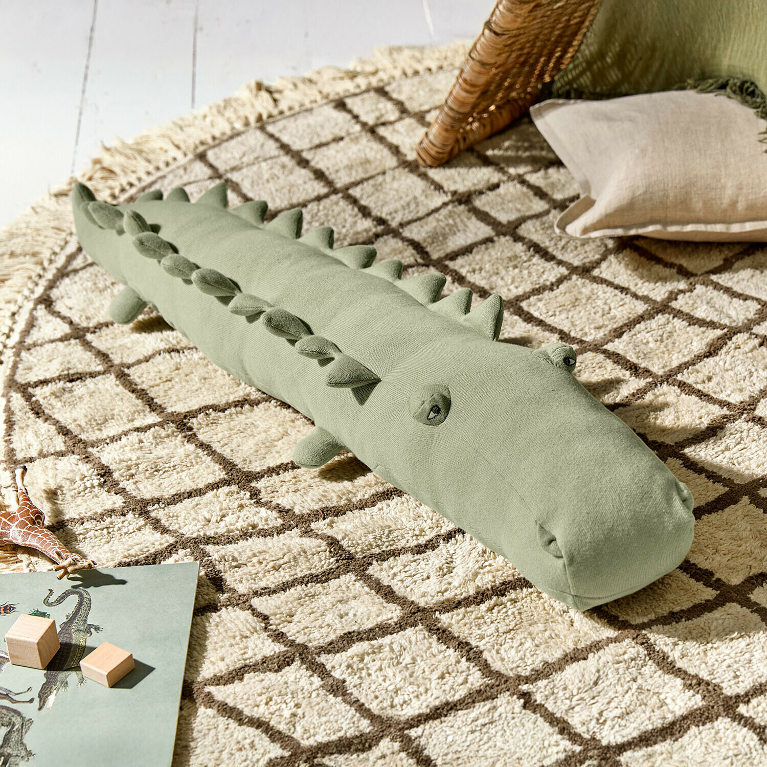 Peluche Zimpy Cuscino morbido verde a forma di coccodrillo su tappeto beige con motivo geometrico