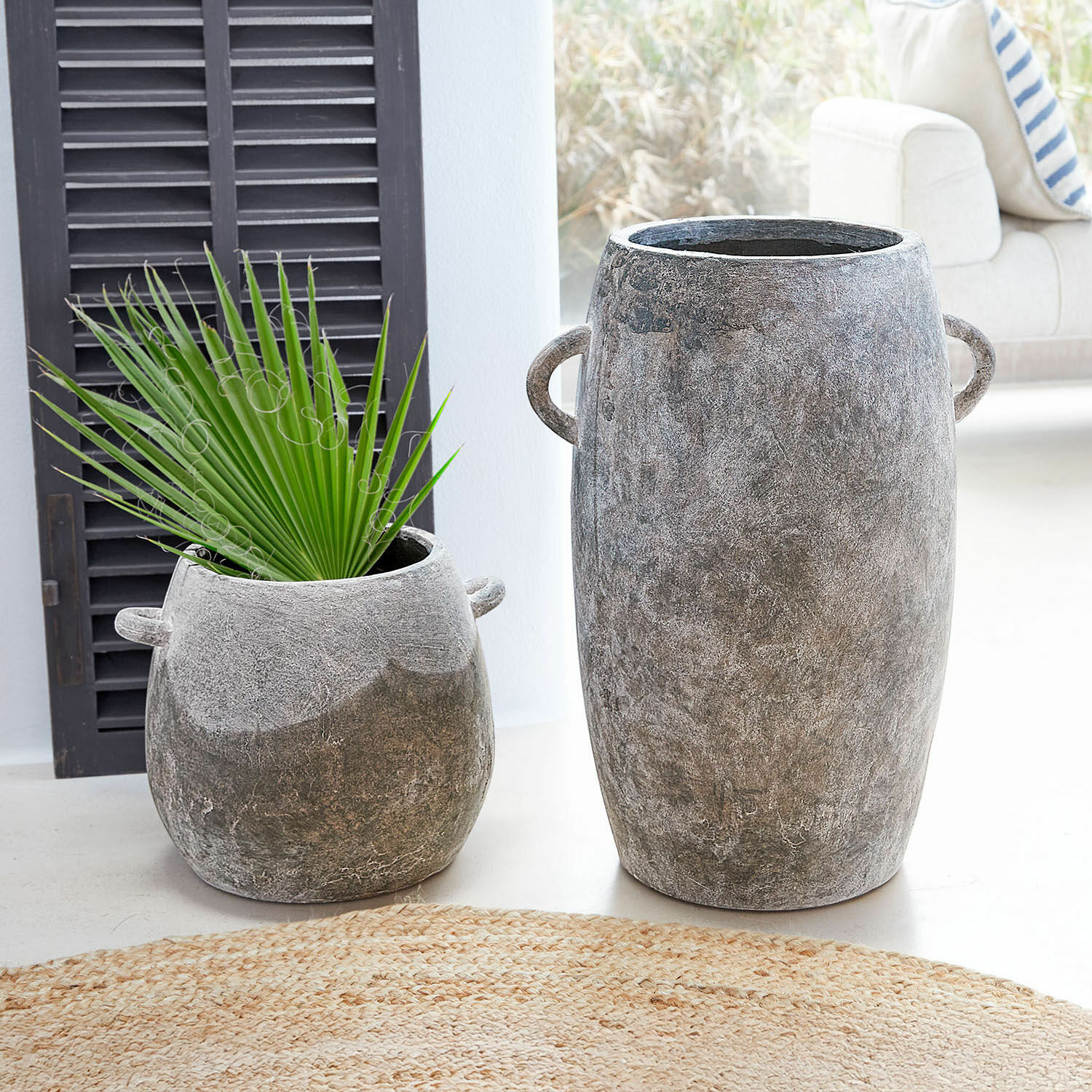 Coppia di portavasi Cœuron Due vasi in cemento grigio di diverse dimensioni con manici, uno con foglia verde, decorazione d'interni