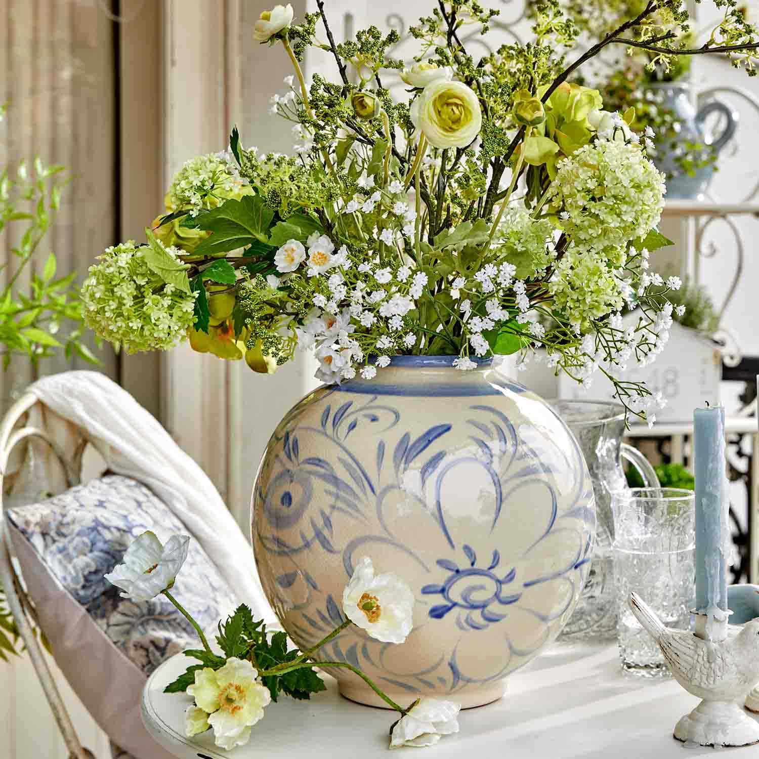 Vaso in ceramica rotondo con motivo floreale blu e mazzo di fiori verdi e bianchi su tavolo